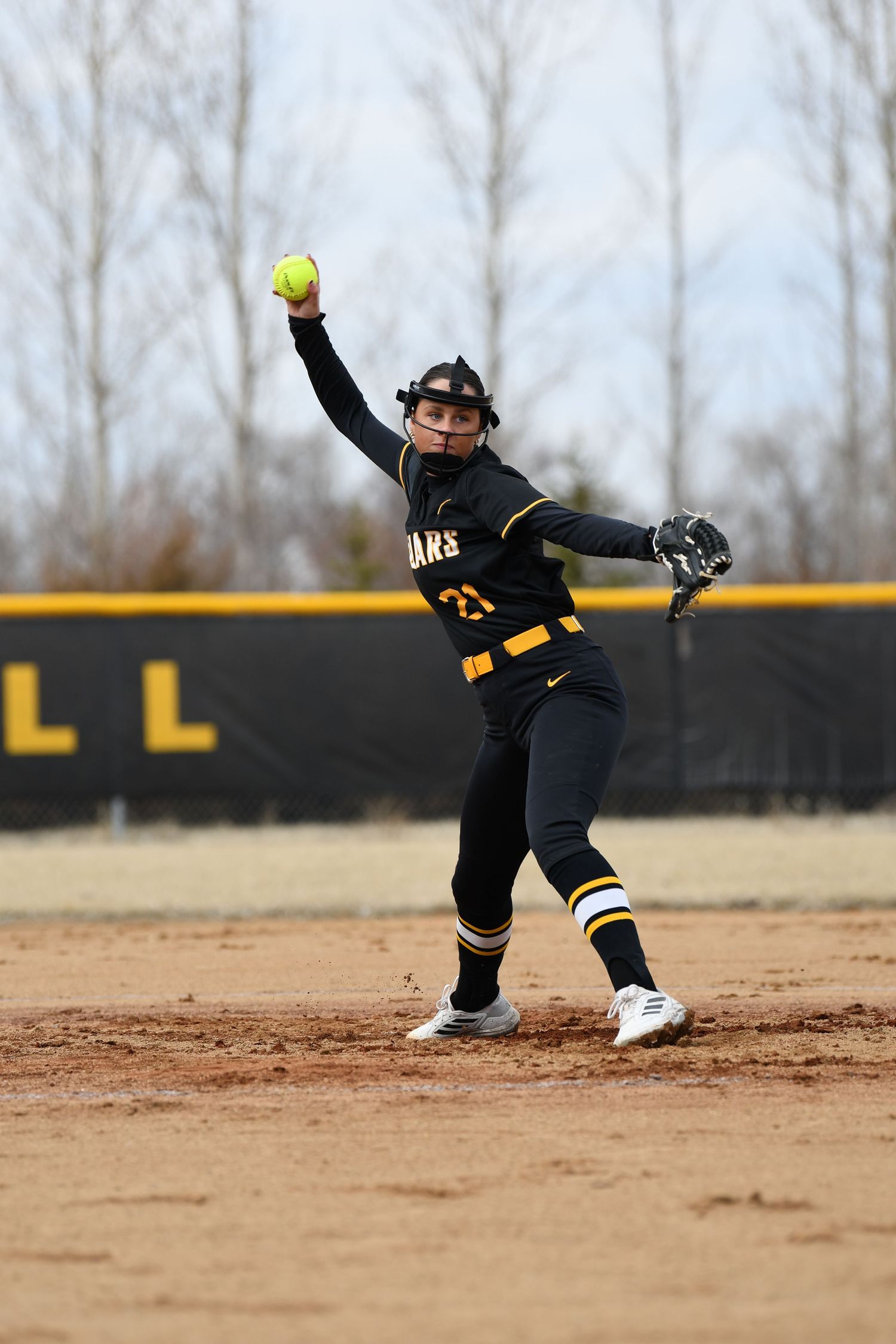 Softball infielder stretches to make athletic play on dirt field.