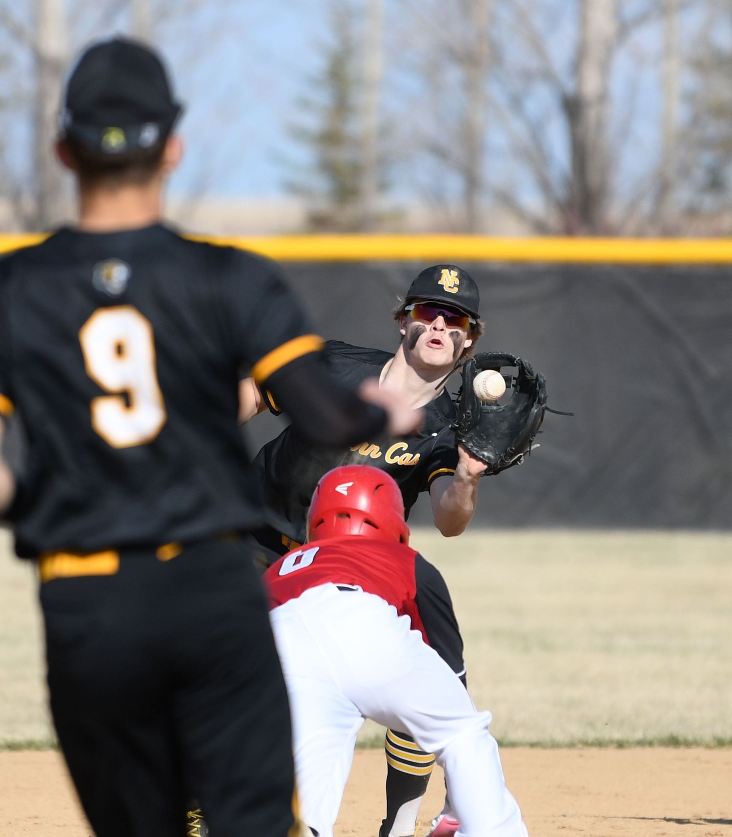 Baseball players from opposing teams compete for a catch during an intense game.