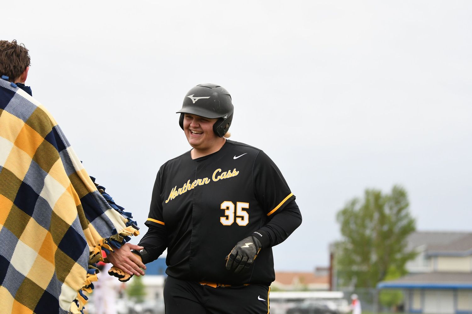 Baseball players in black and gold uniforms during game action.