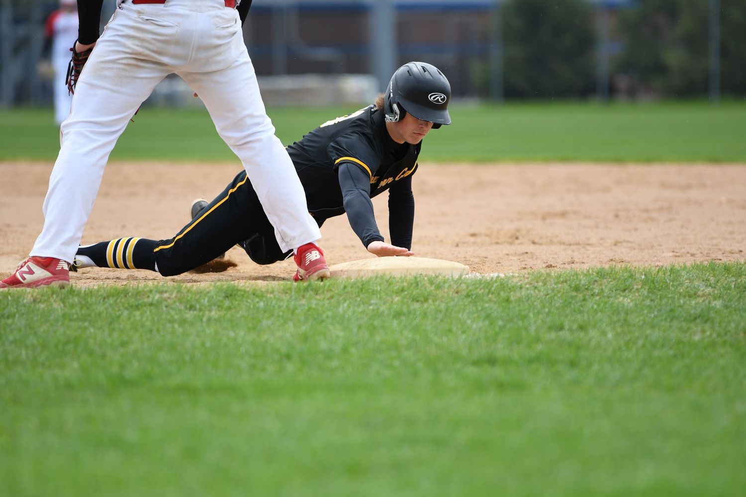 Baseball players positioned near base during gameplay on grass field.