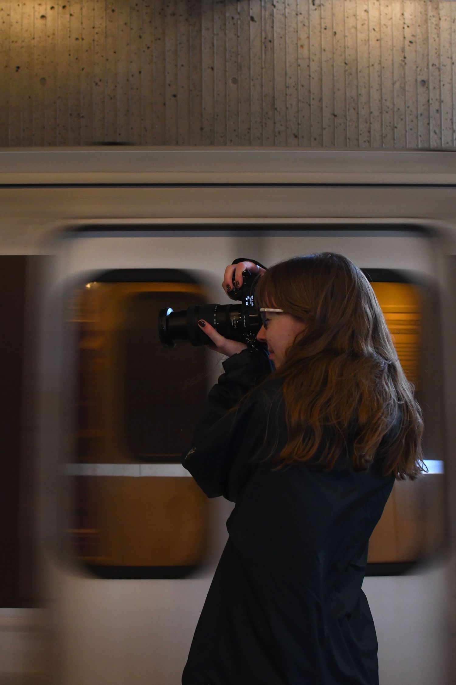 Photographer capturing shots of a passing train in a subway station.