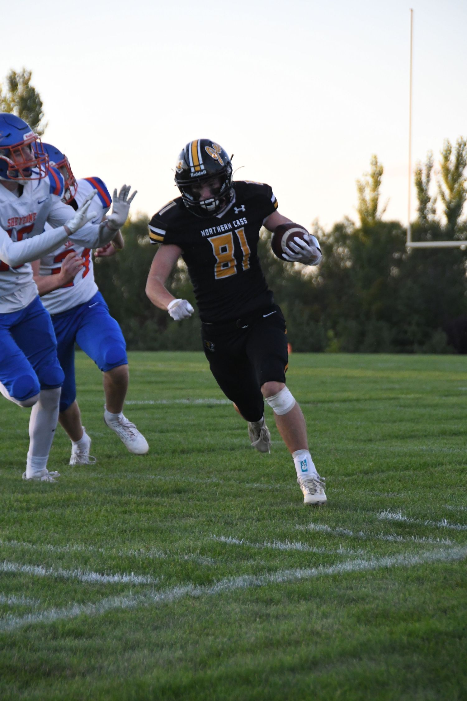 Football player making horizontal diving catch during game on grass field.