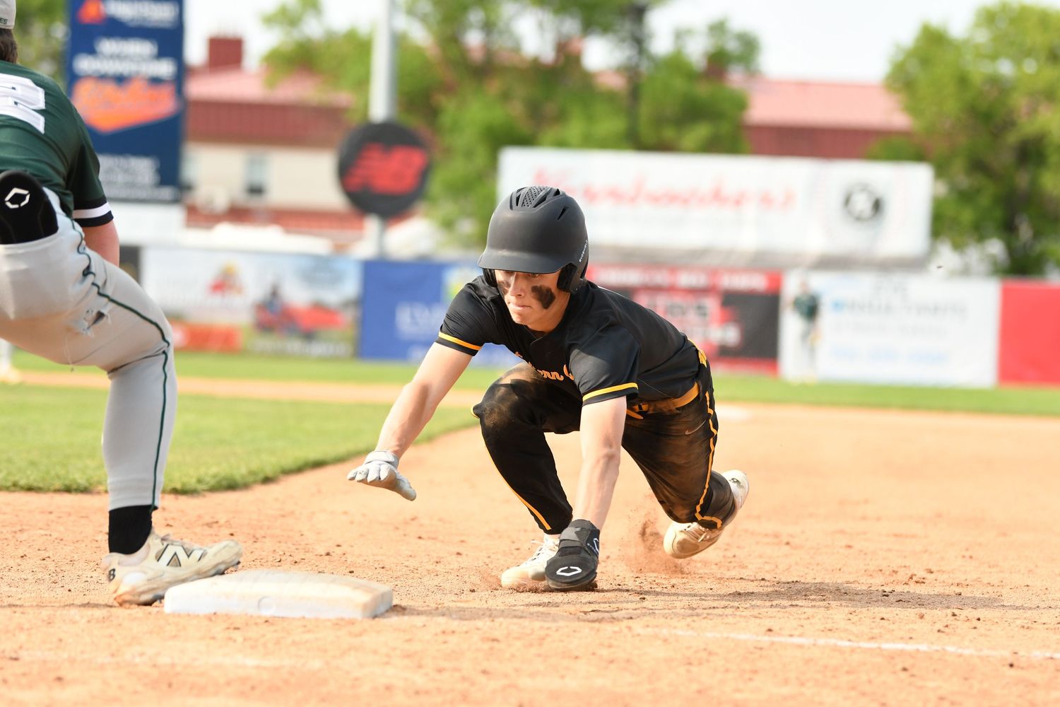 Baseball players practicing sliding techniques on the infield dirt during training.