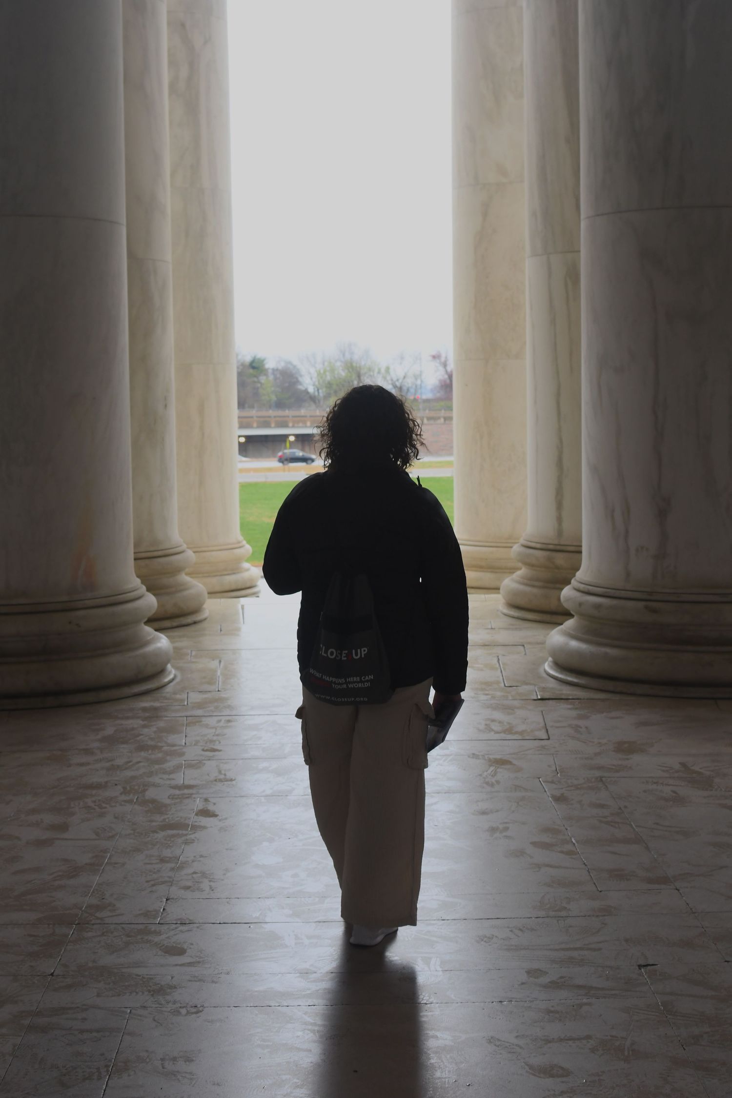Silhouette of a person standing between marble columns in dramatic lighting.