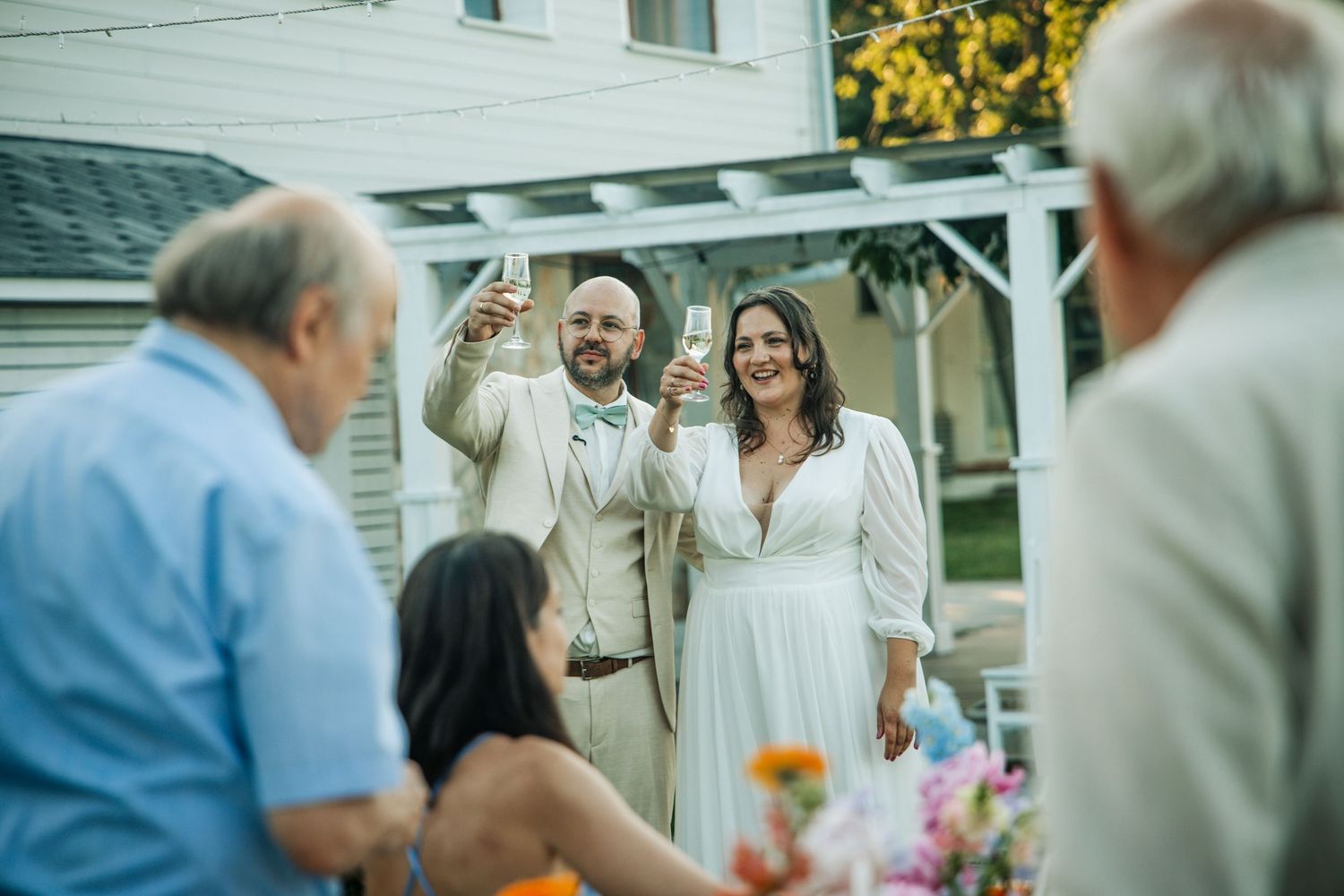 Bride and groom toasting champagne with guests at an outdoor backyard wedding reception.