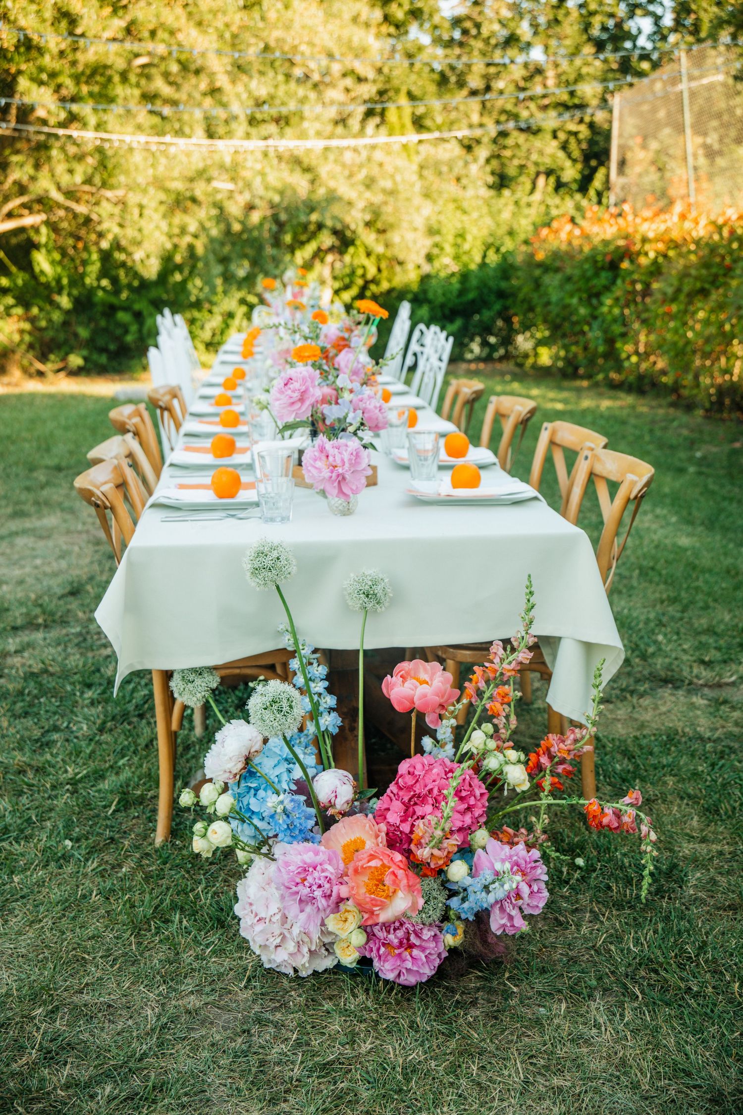 Elegant outdoor garden wedding reception table with colorful floral arrangements featuring pink hydrangeas and peonies.