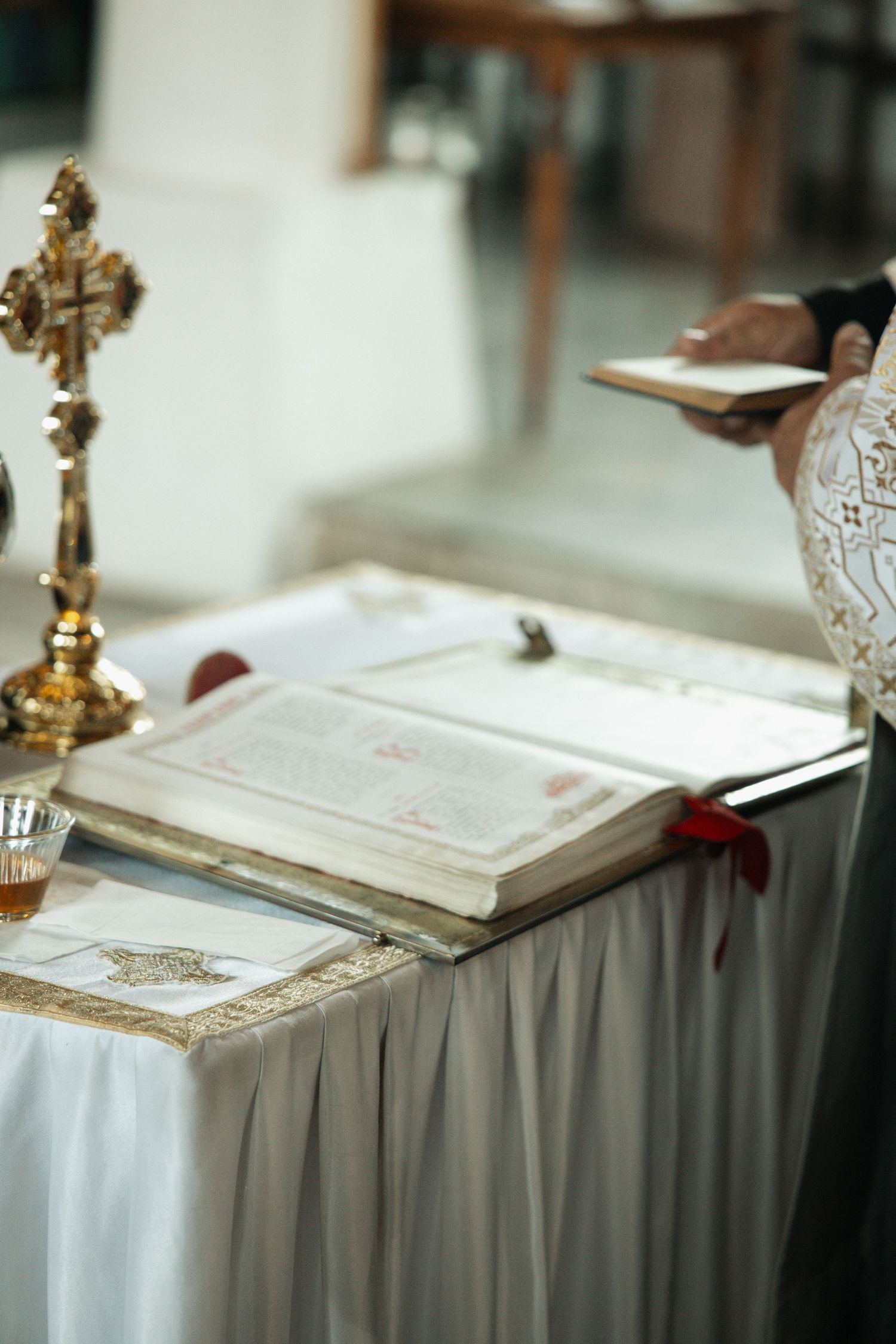 Orthodox Christian wedding altar with open Bible, golden cross, and ceremonial items on draped table.