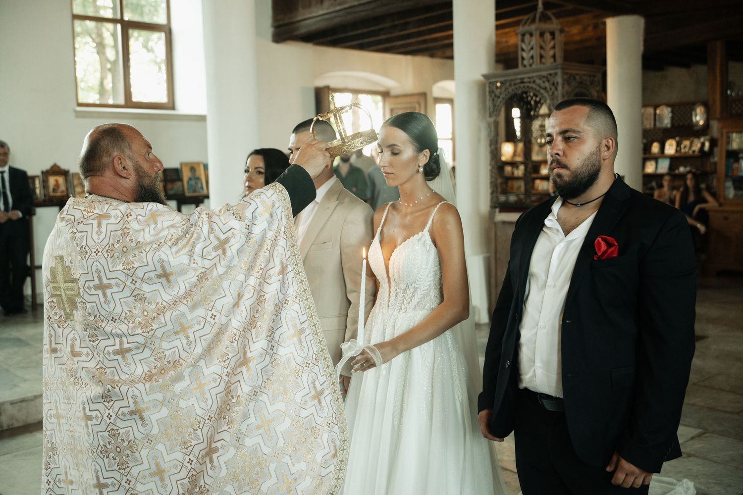 Orthodox priest in gold vestments performing wedding ceremony with bride and groom inside historic church.