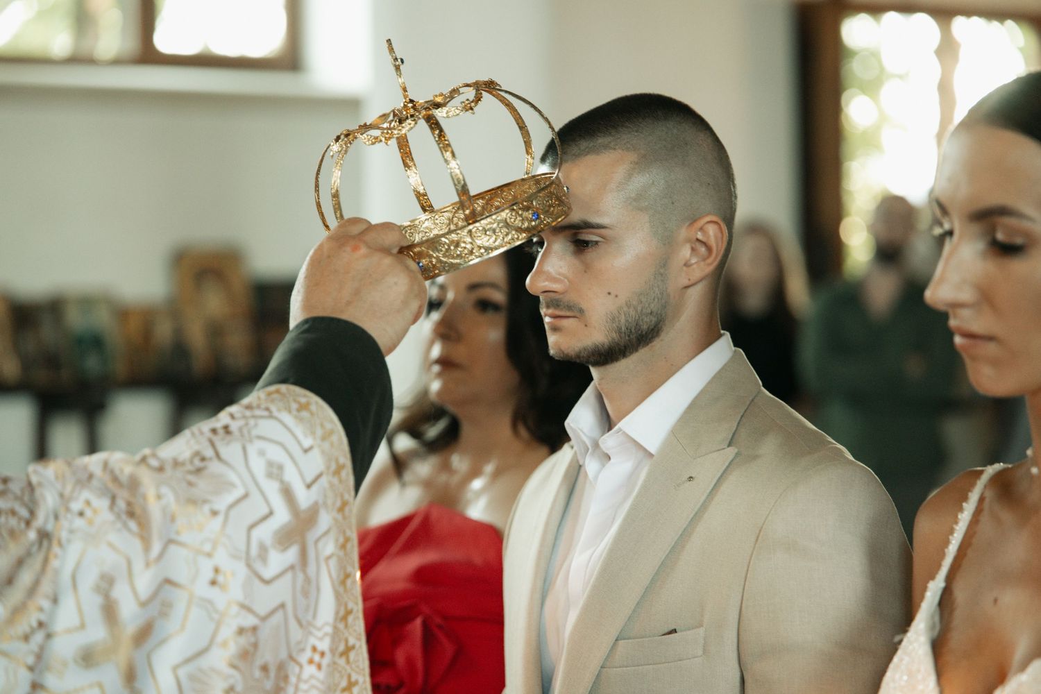 Orthodox priest placing a golden crown on the groom during a religious wedding ceremony.