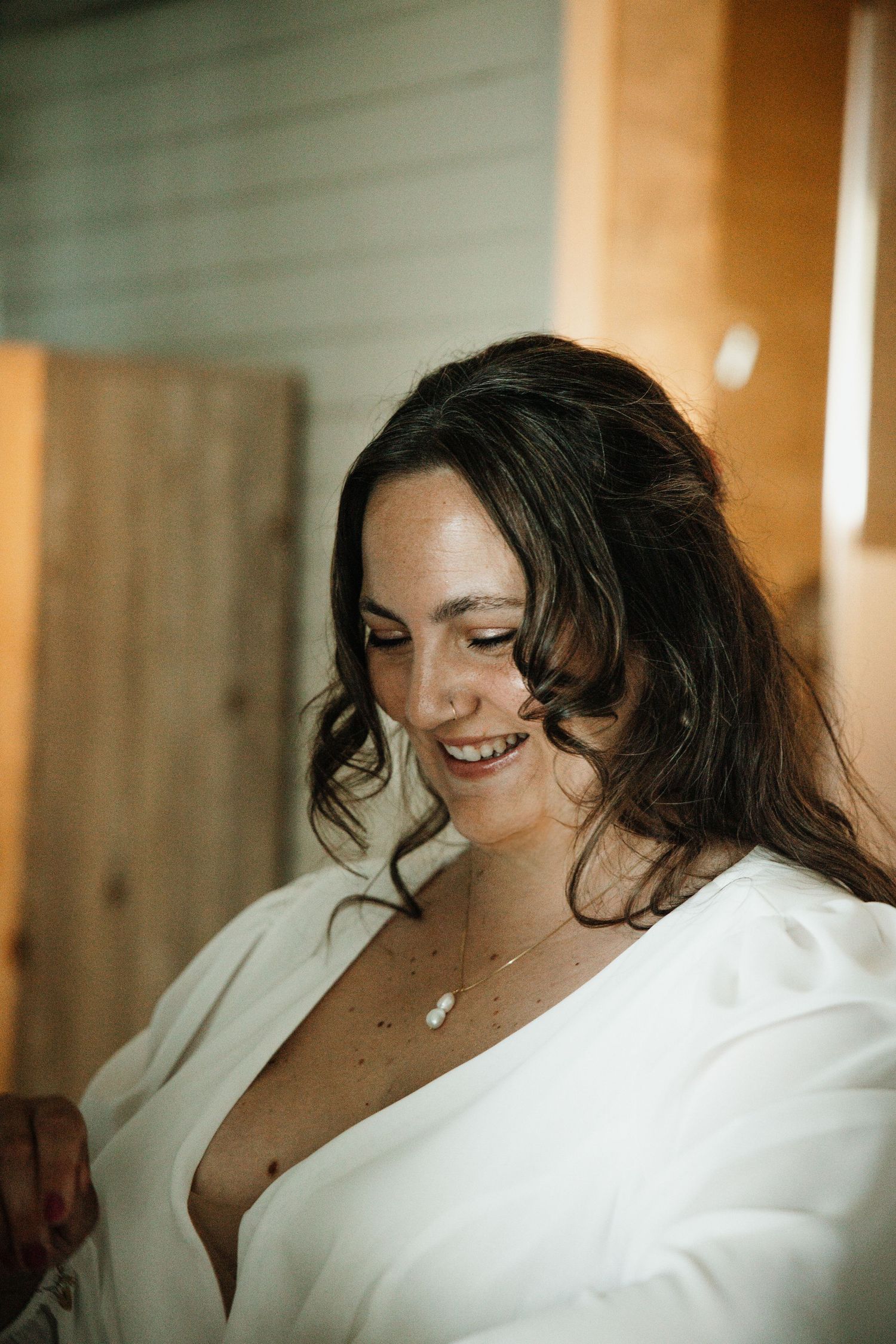 Smiling brunette bride in white robe getting ready for her wedding ceremony.