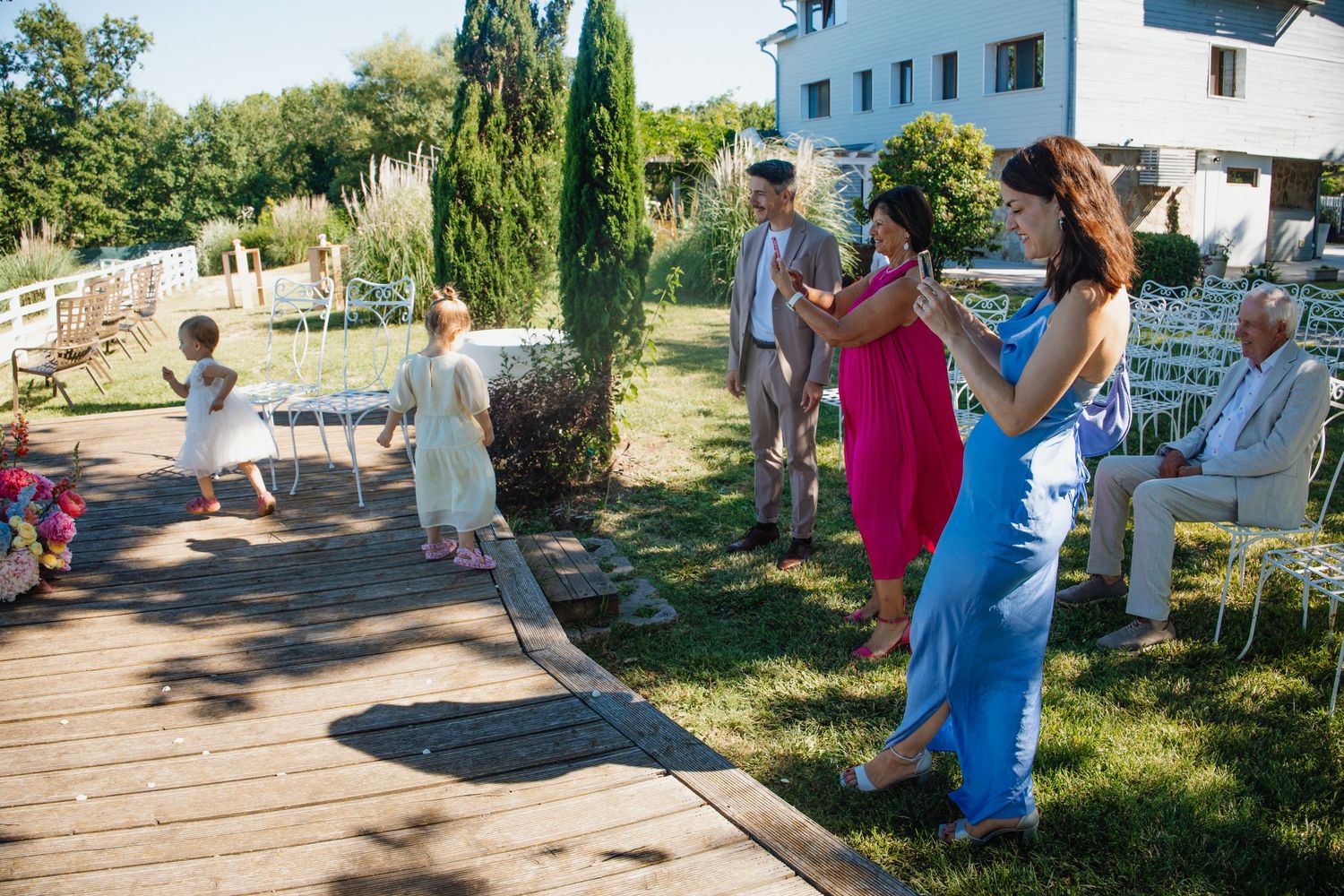 Guests dancing and socializing outdoors at a garden wedding ceremony on a sunny summer day.
