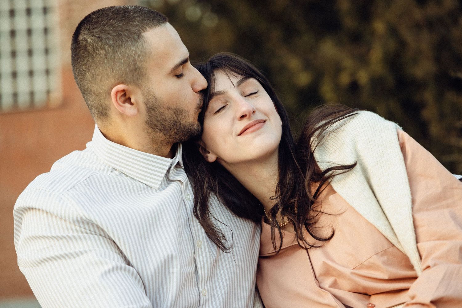 A romantic couple shares tender moments in a series of intimate engagement photos outdoors.