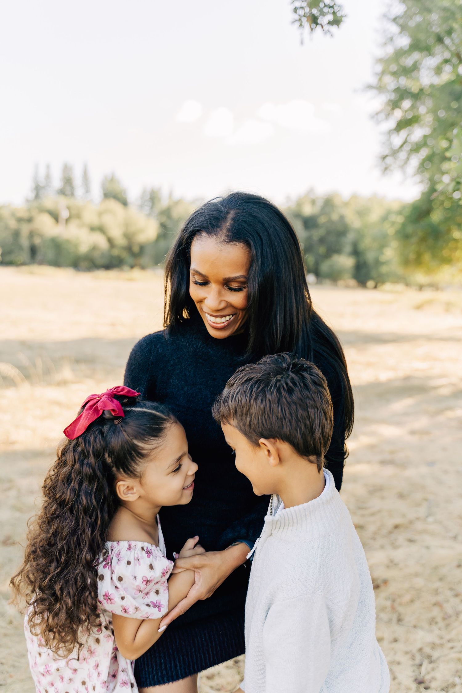 Sweet family portrait showing tender moments of connection and joy in a sun-dappled outdoor setting.