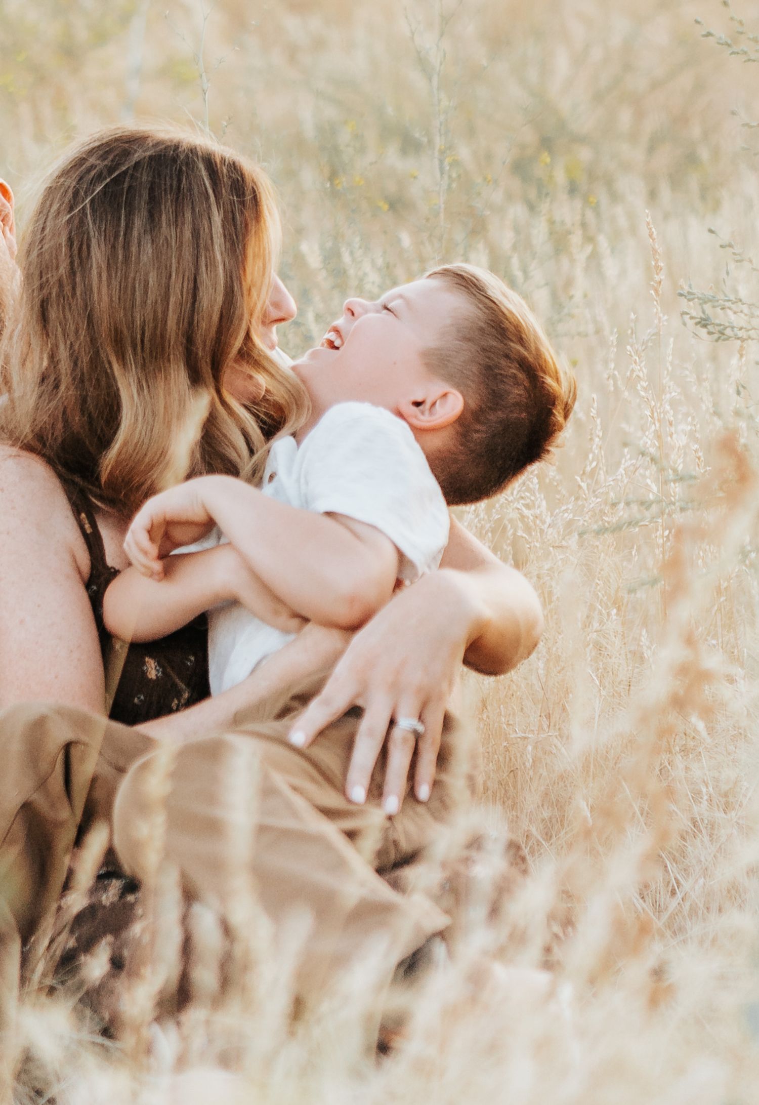 Mother and child share tender moments while laying in soft golden grass.