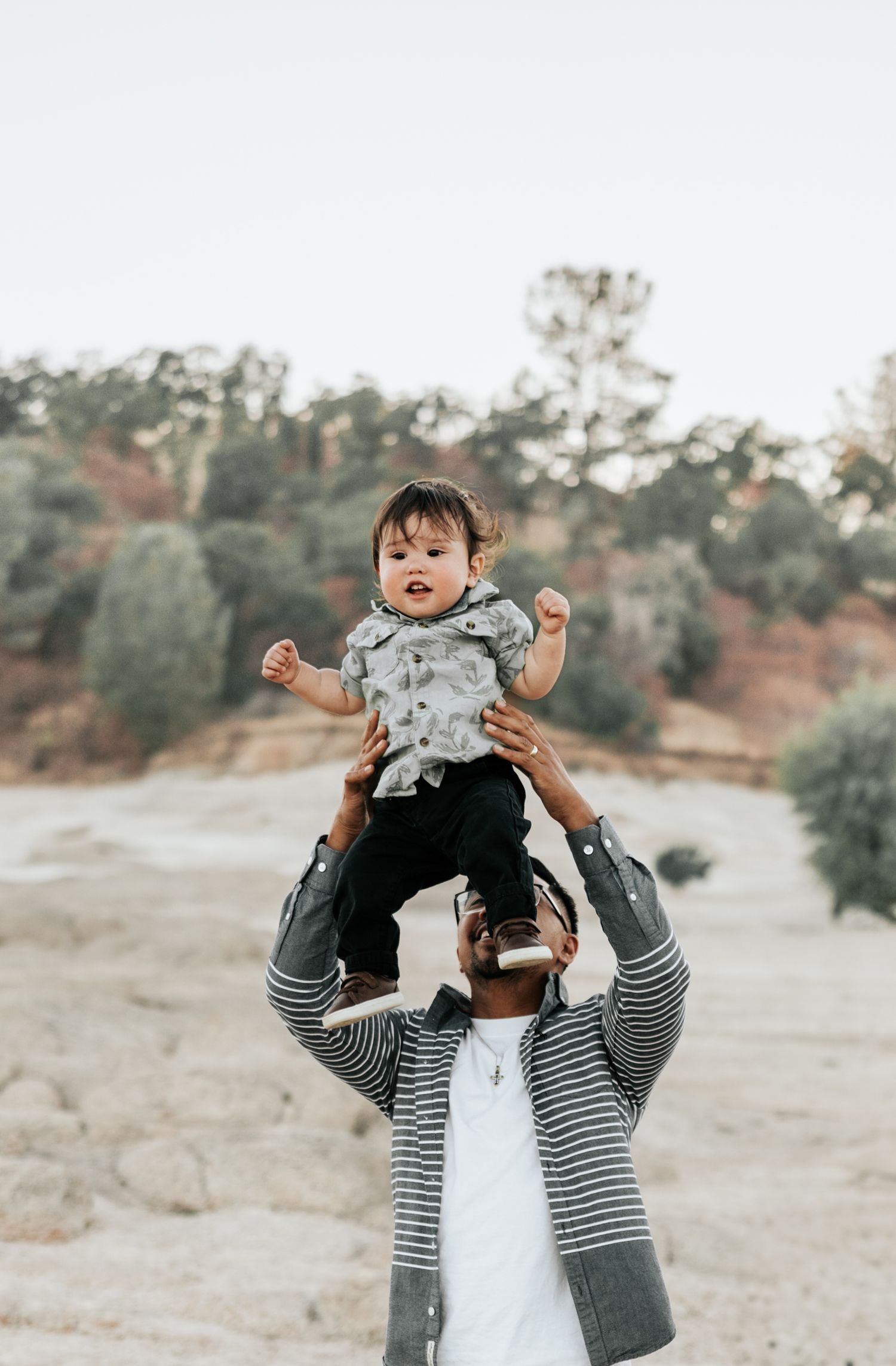 A joyful candid moment captured outdoors showing playful interaction against a natural backdrop.