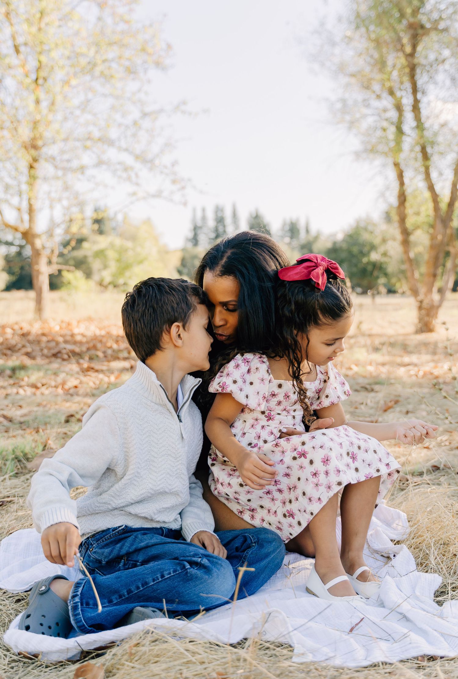 A heartwarming family portrait taken outdoors with everyone gathered close on a white blanket.