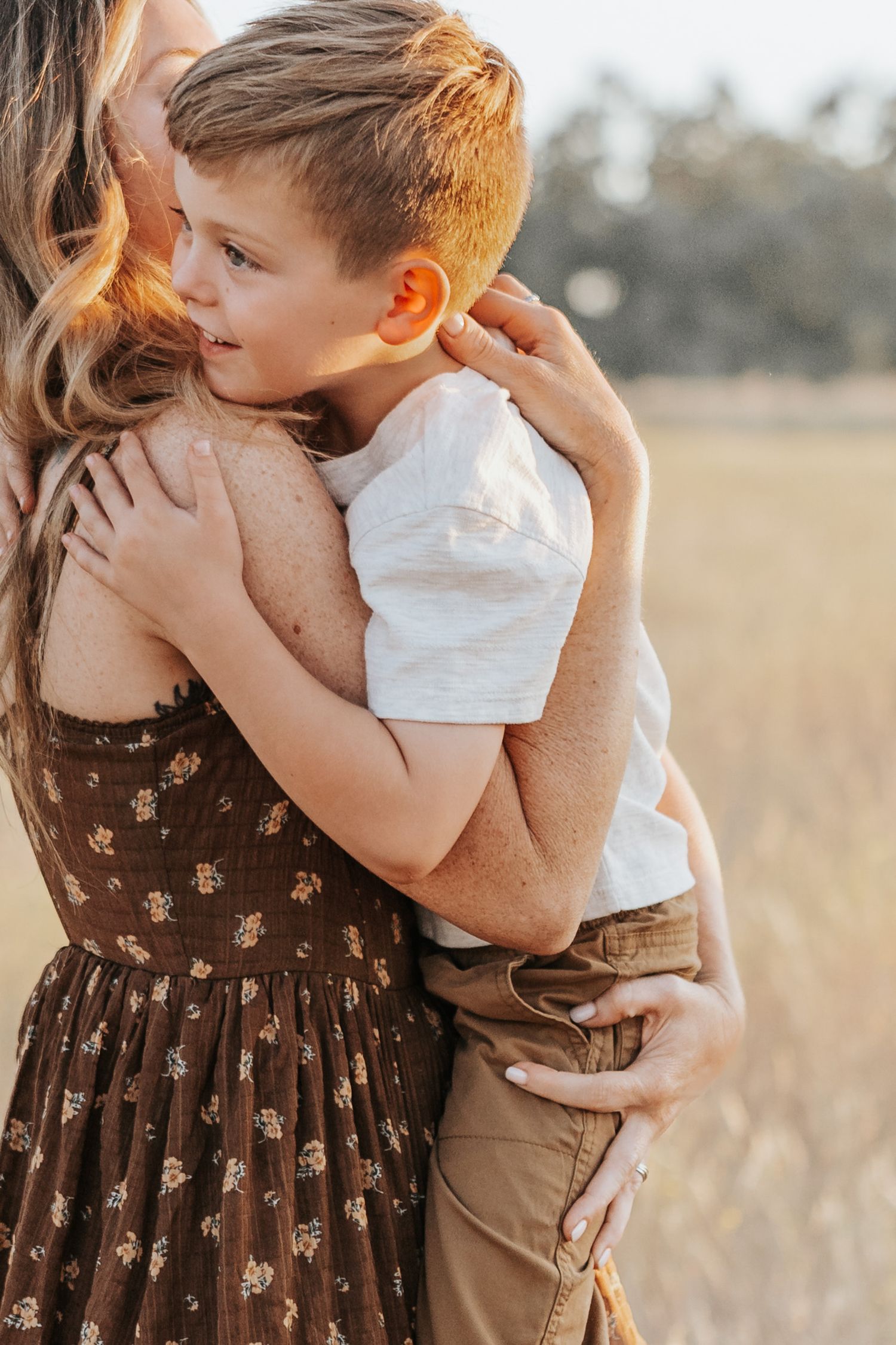A tender moment of embrace between parent and child in a golden field at sunset.