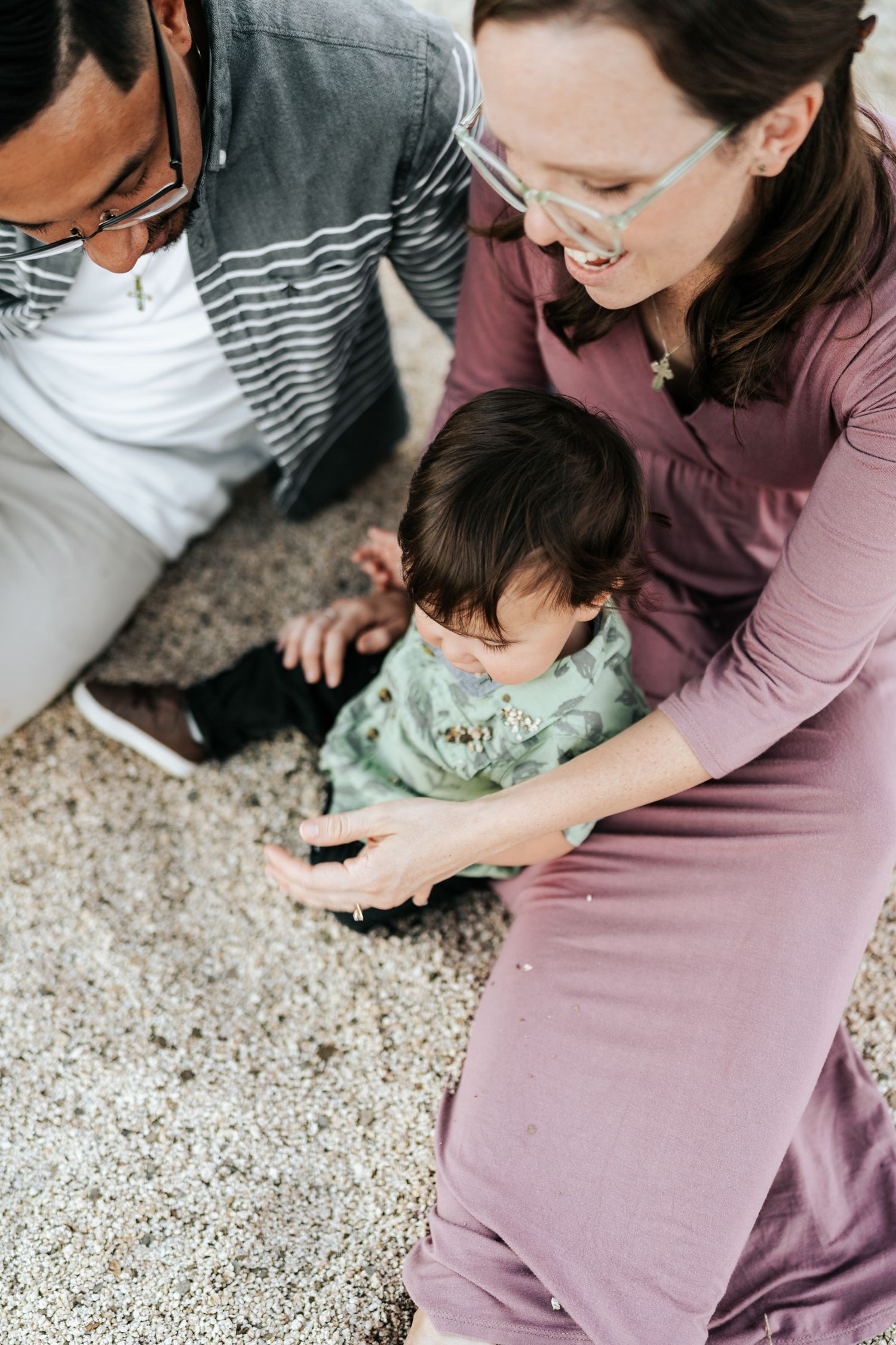 A family playing together on a light colored carpet in coordinating mauve and striped outfits.