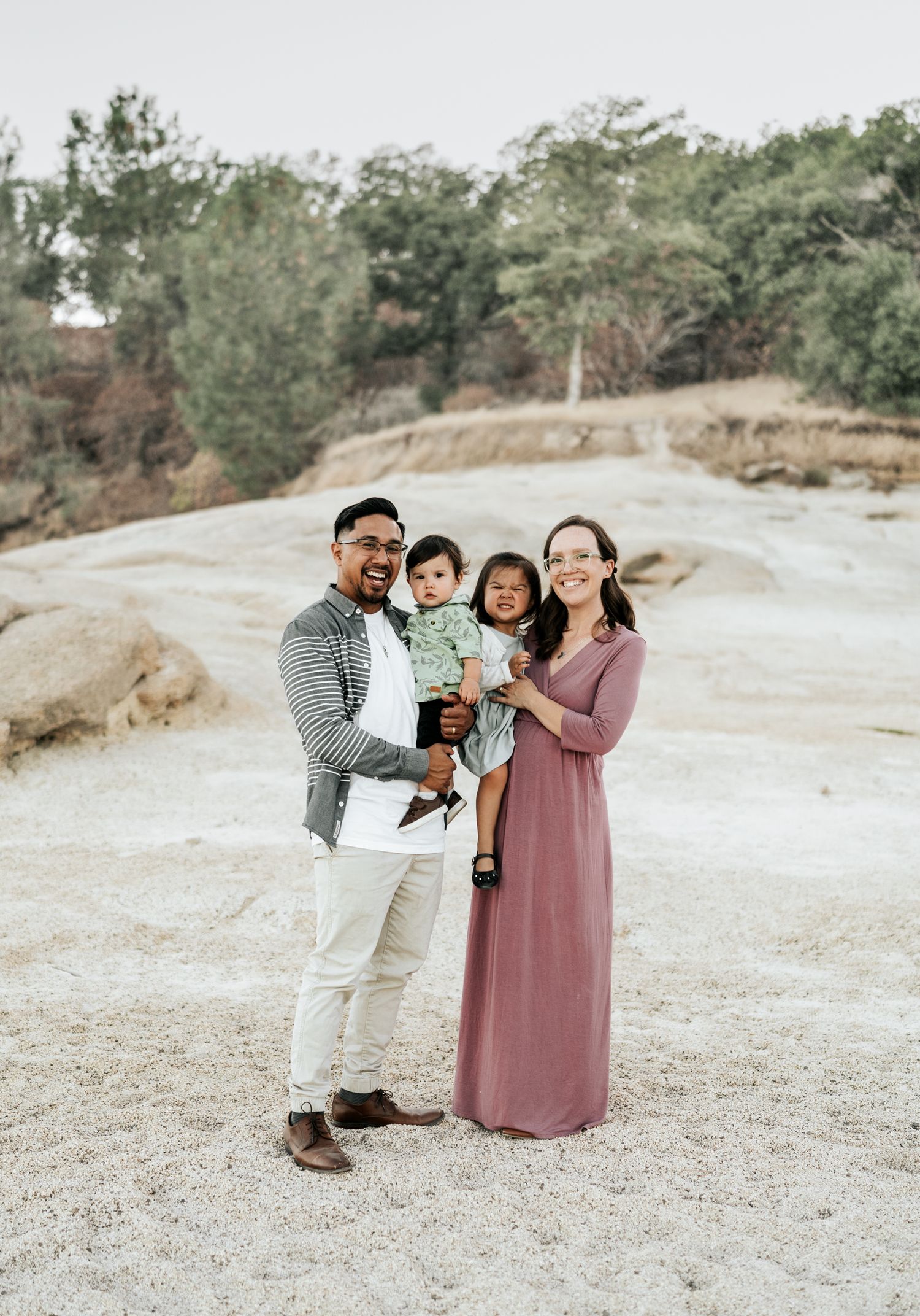 A family shares a candid moment together outdoors in nature with soft lighting and muted earth tones.
