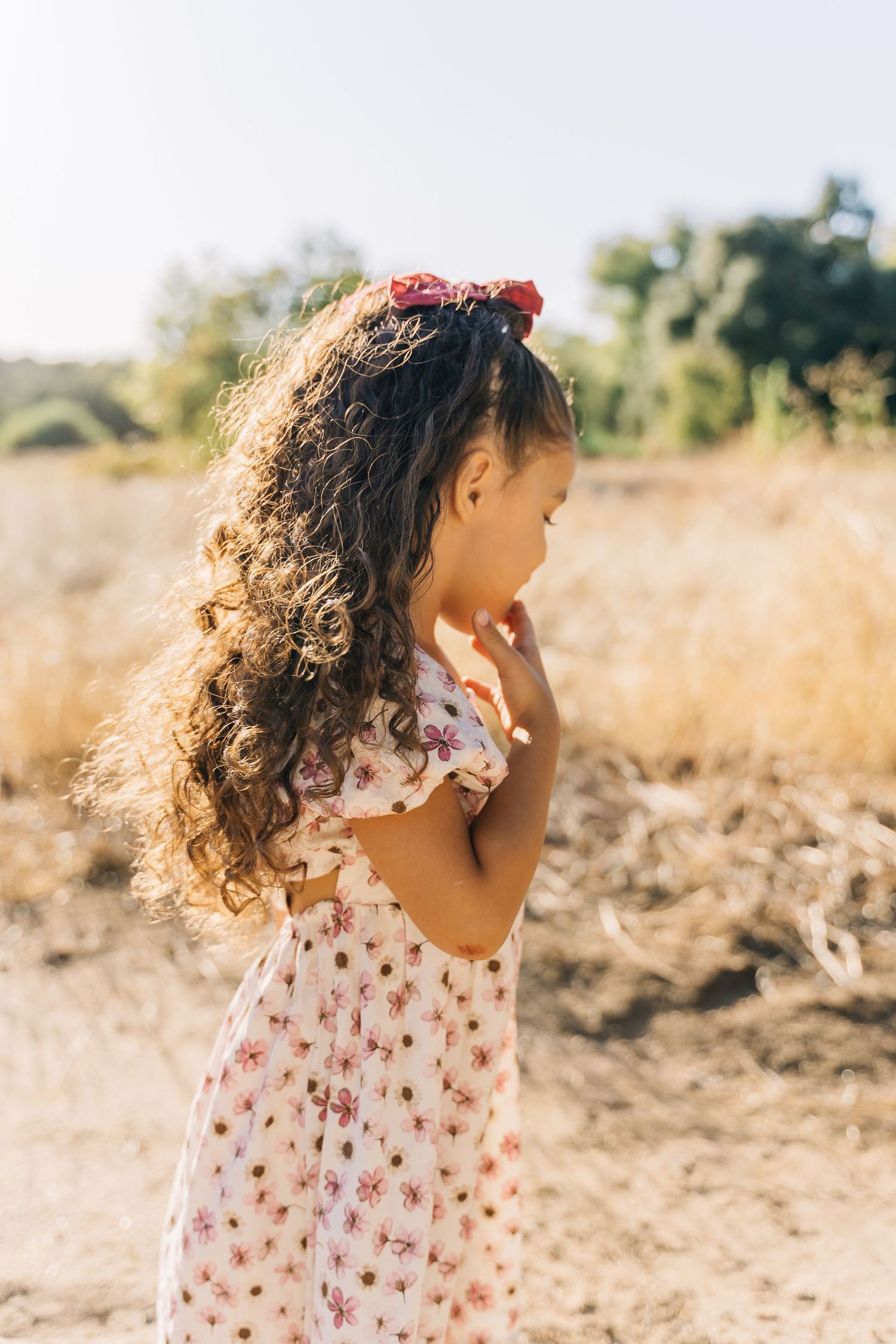 A series of candid profile shots showing curly hair blowing in the wind against a golden sunlit field.
