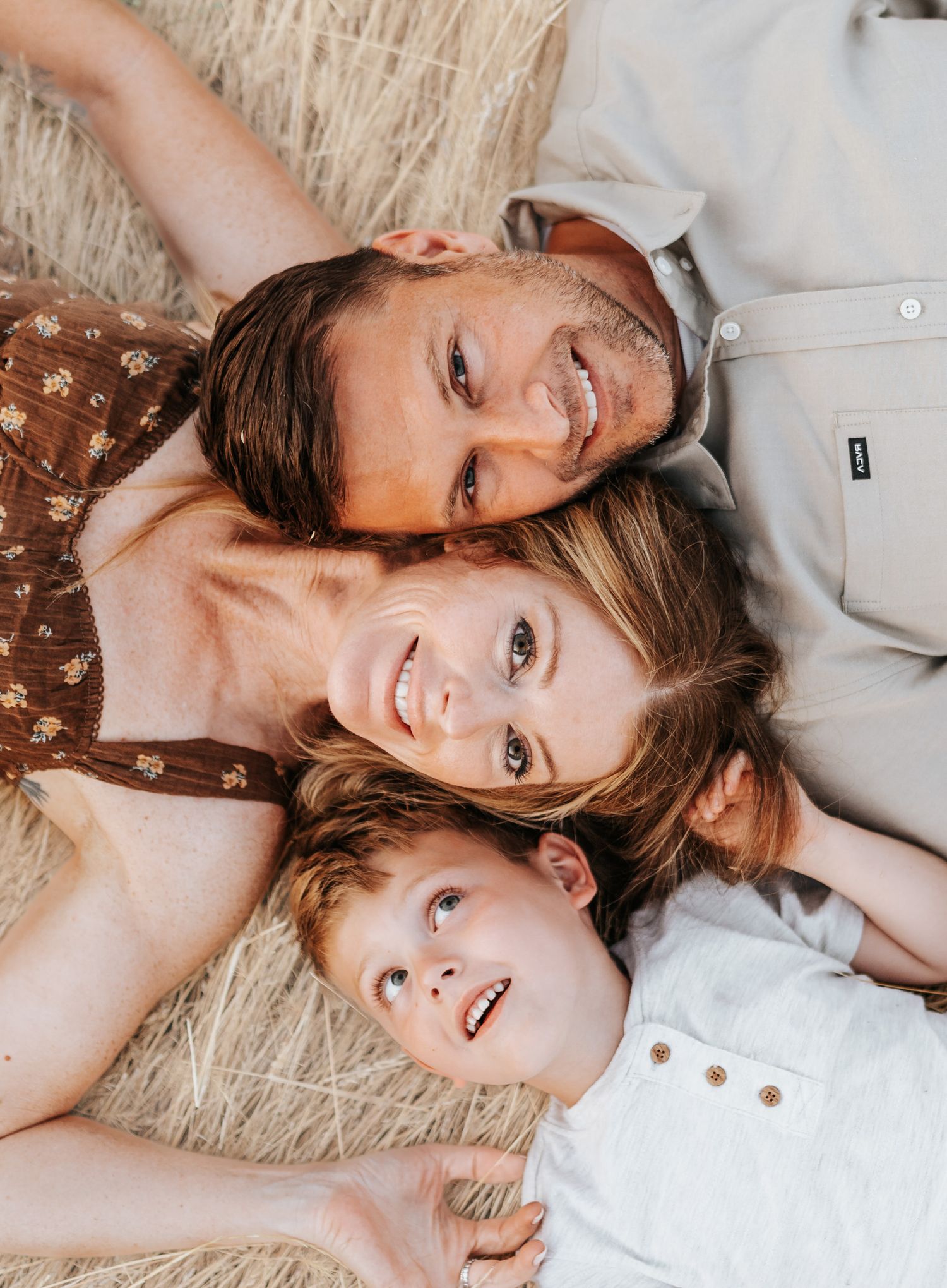 Family lying together in tall grass creating a joyful portrait moment.