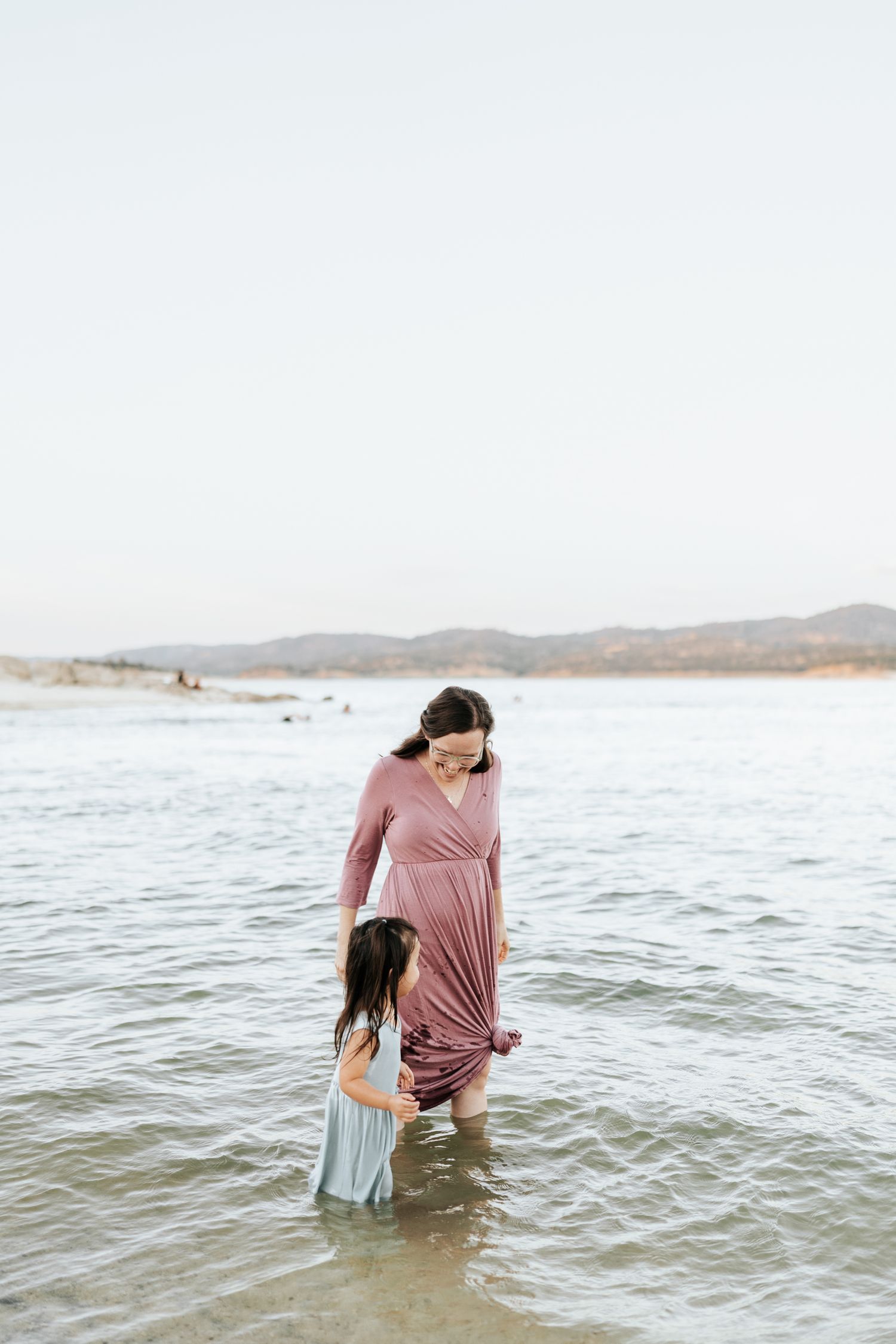 A couple shares playful moments together in the ocean waves during a beach photoshoot.