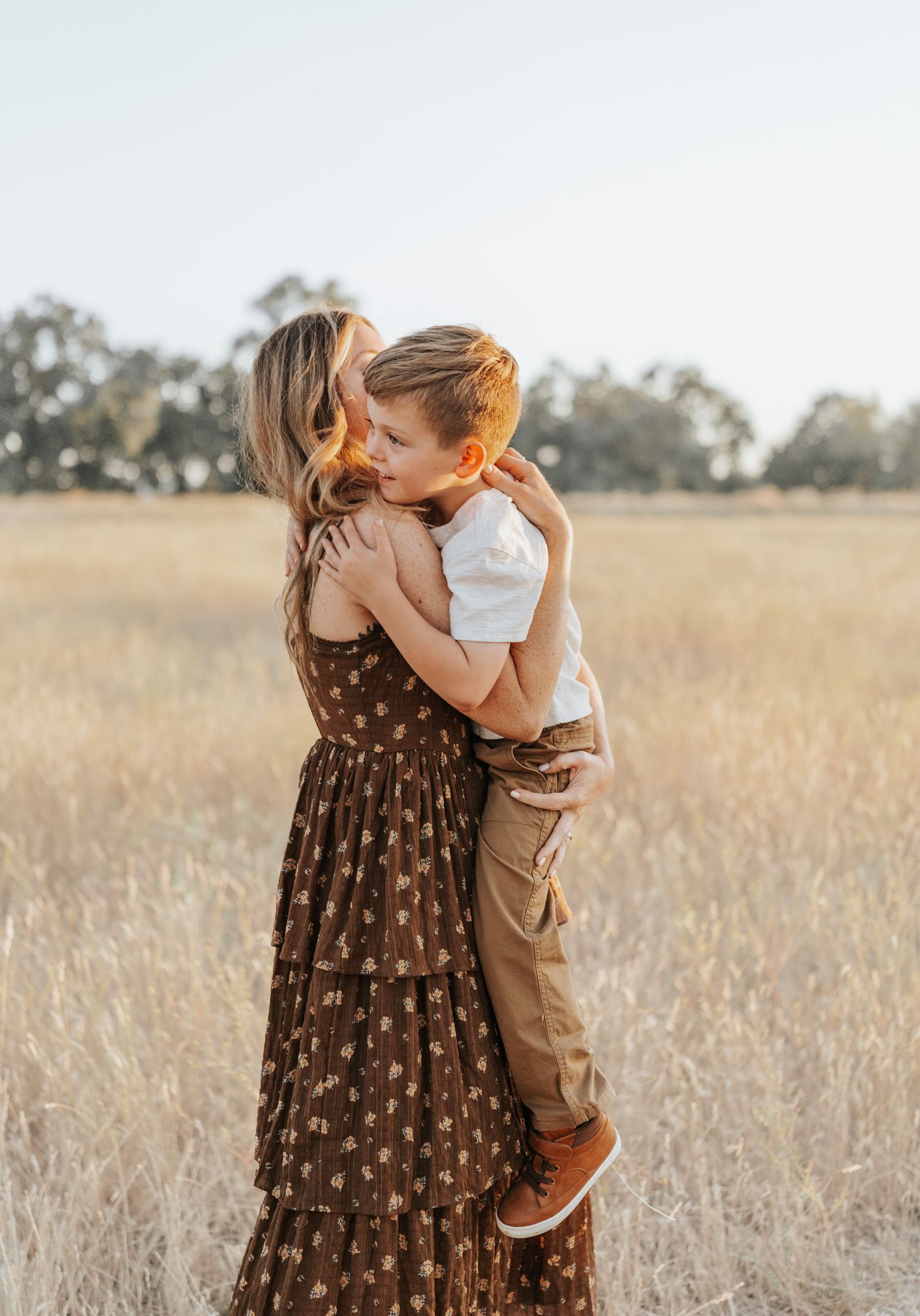 Intimate family portrait showing tender embraces against a golden field at sunset.