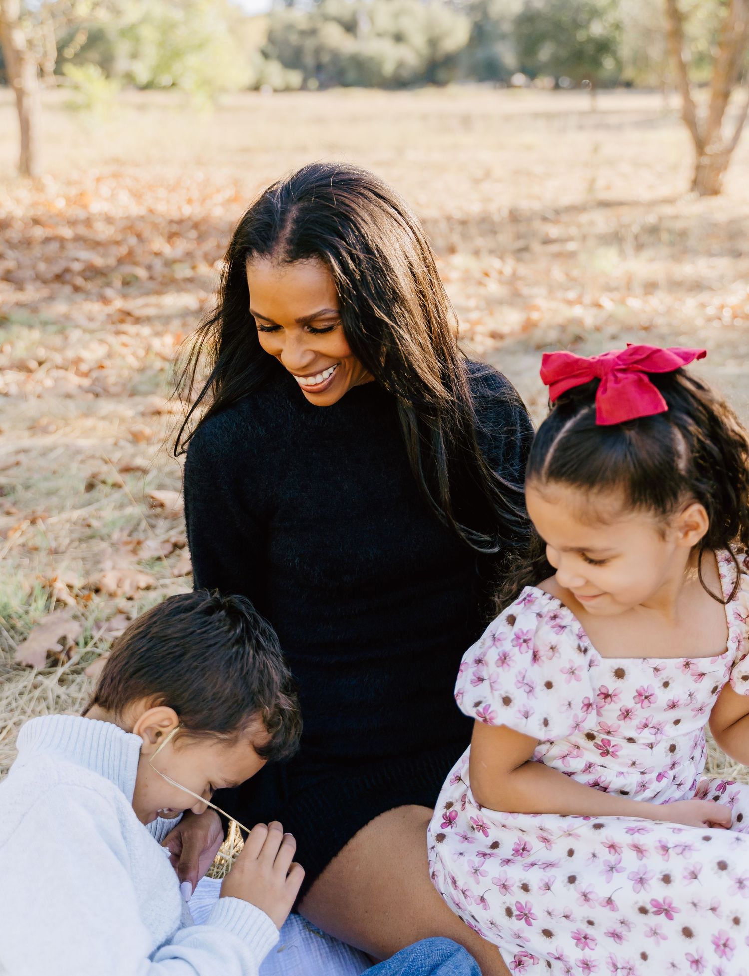 A candid moment of laughter and embraces during a family photo session in a sun-drenched field.