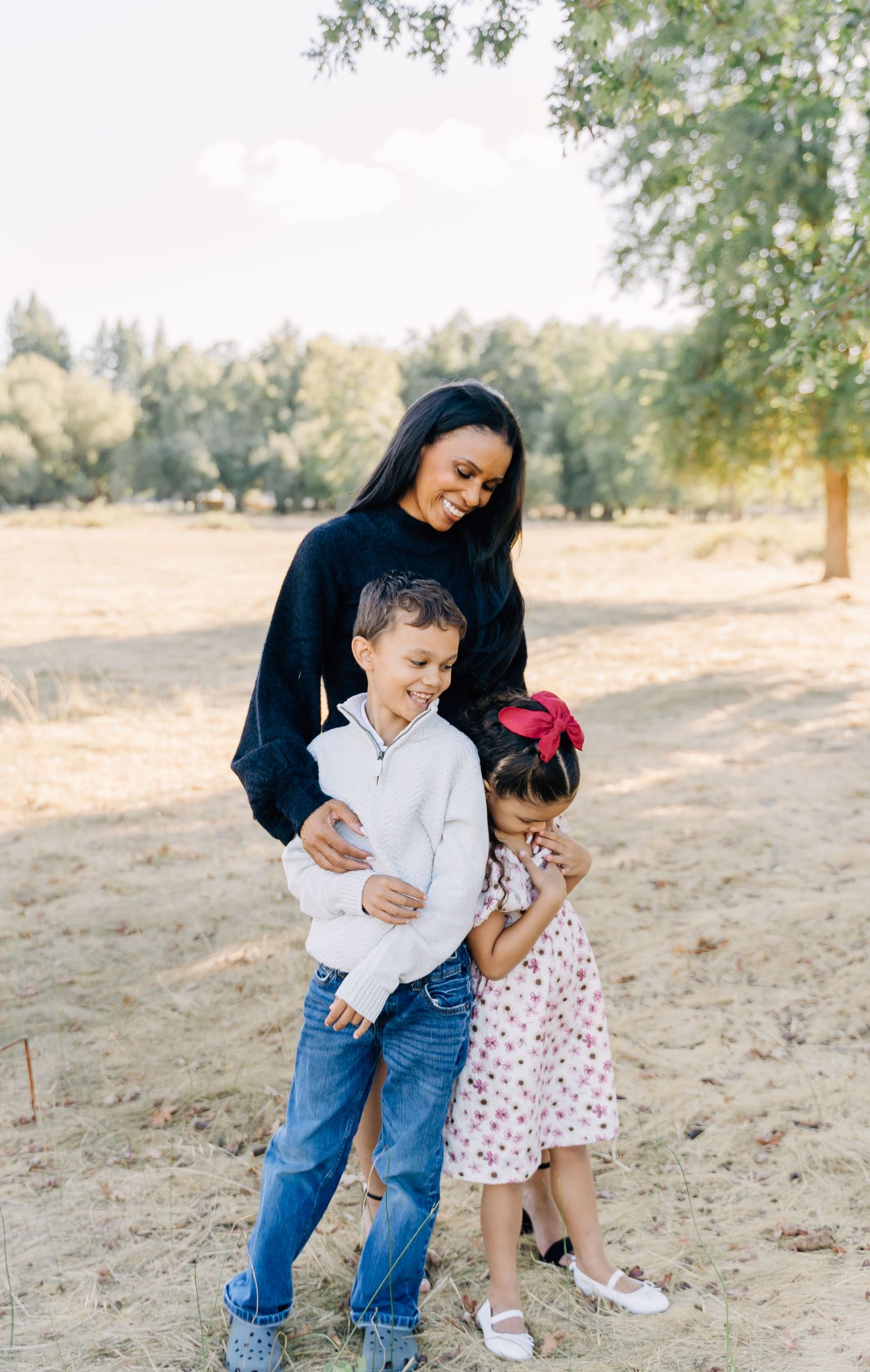 A playful outdoor family moment captured in warm sunlight showing affectionate interaction on sandy ground.