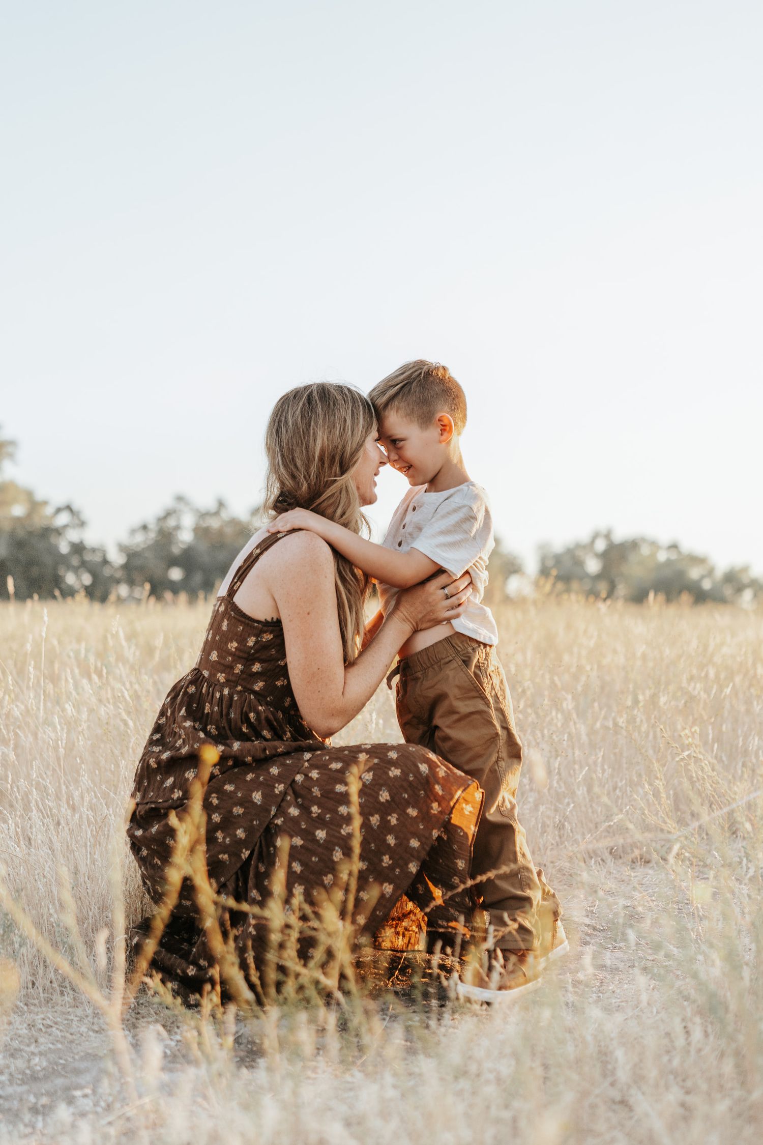 A tender moment between parent and child embracing in a sunlit golden field.