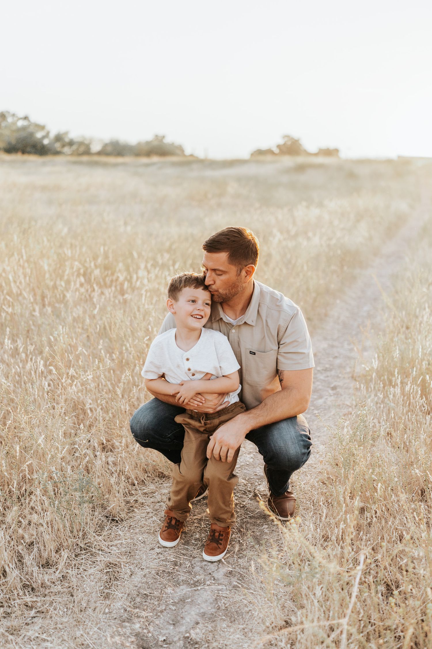 A heartwarming family moment shared in a sunlit meadow of tall grass.