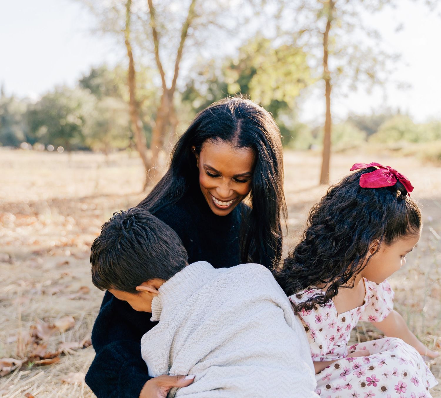 A candid outdoor family photo showing playful interaction between parent and children.