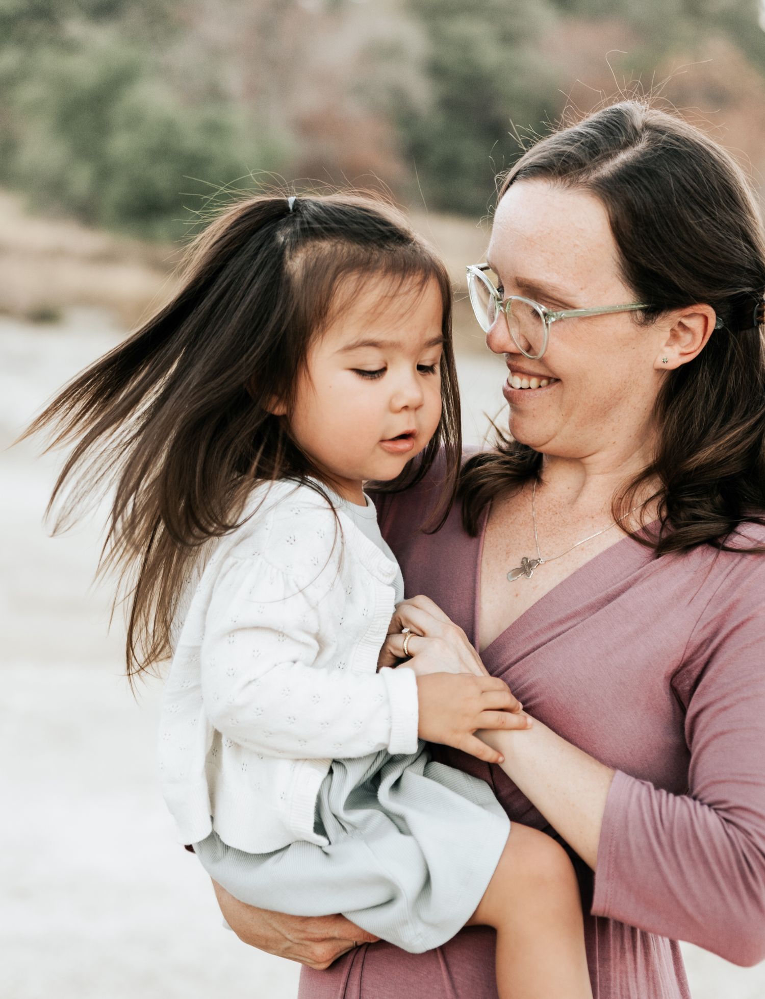 Two people share a joyful candid moment outdoors in soft lighting wearing casual clothing.