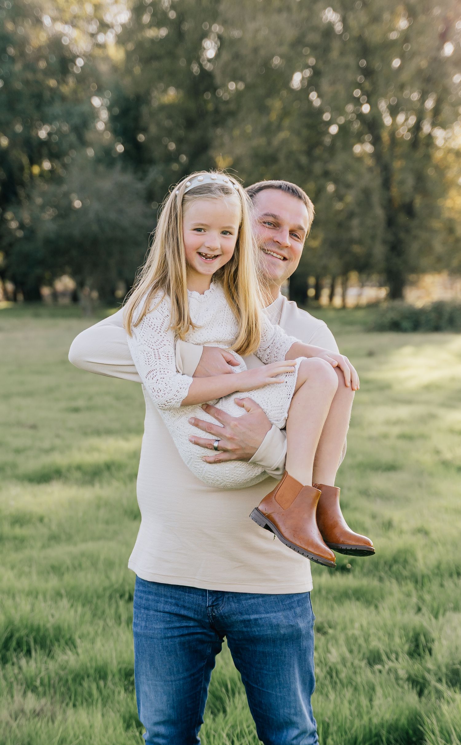 A parent and child share joyful moments together in a sunny green field while wearing casual clothing.