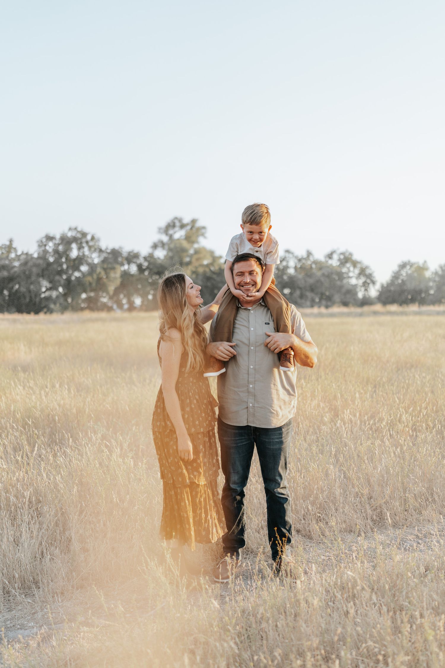A couple embraces in a sun-drenched golden field during a romantic photoshoot at sunset.