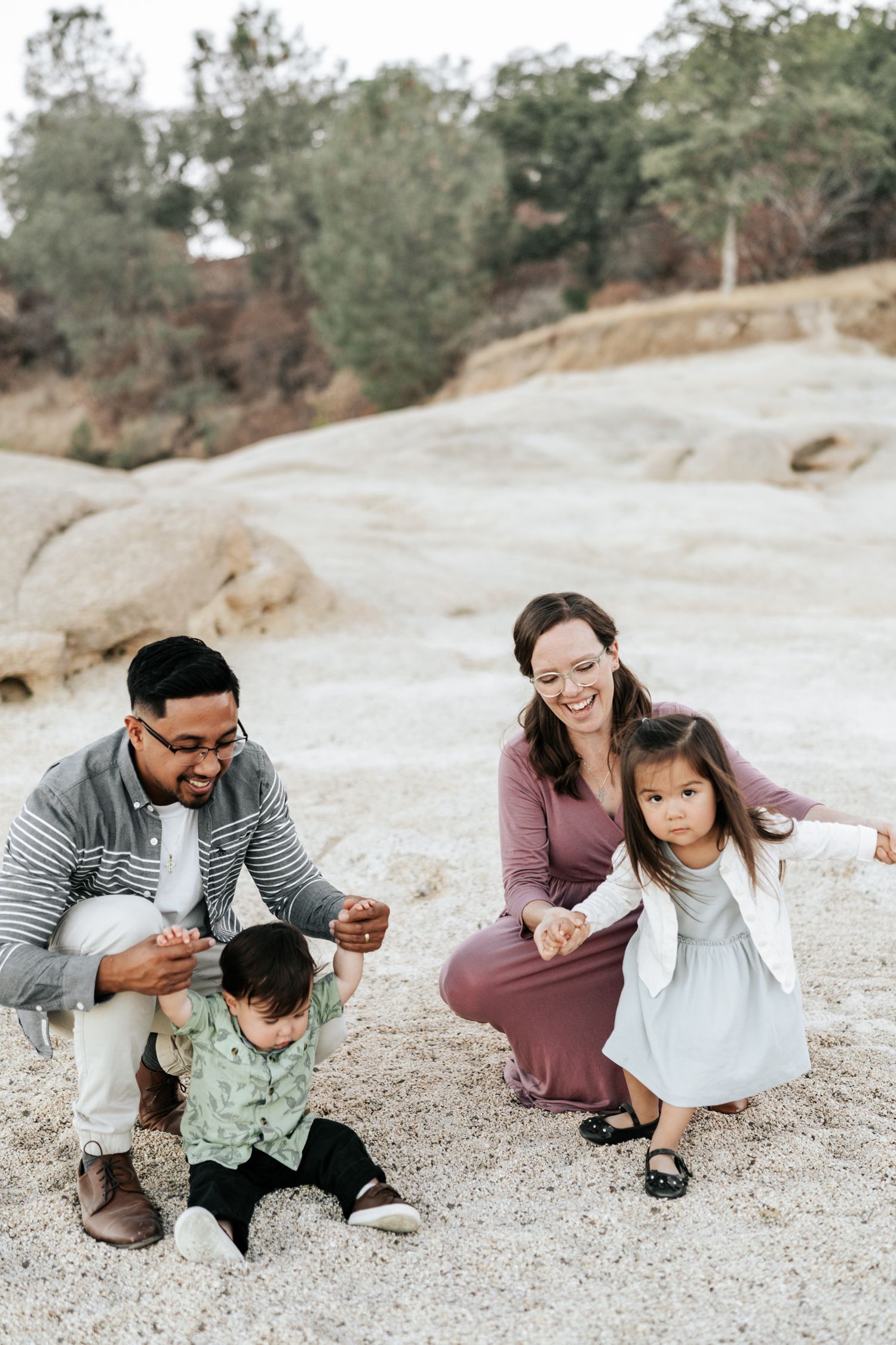 A heartwarming sequence of a family sitting on rocky ground sharing playful moments together.