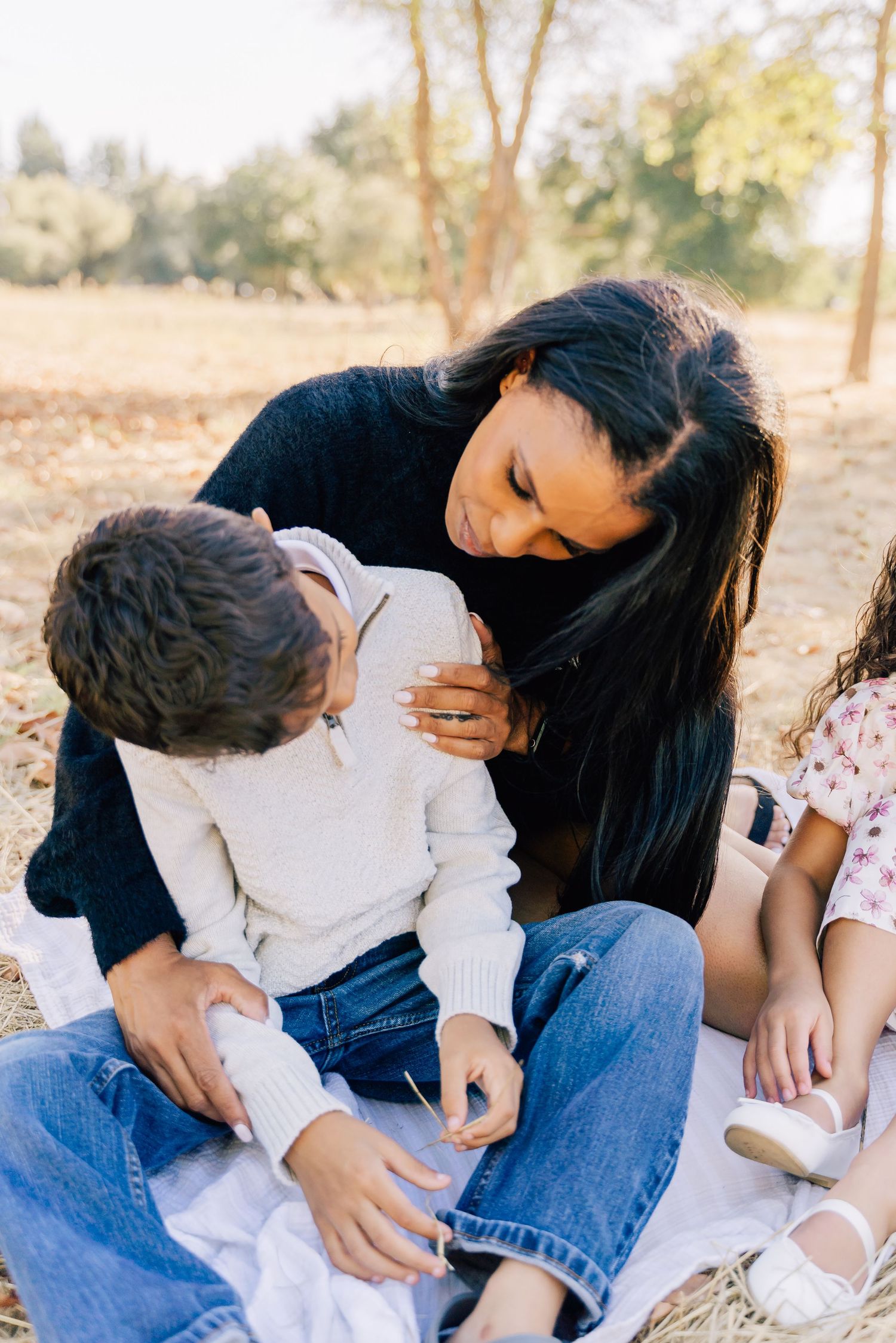 An intimate family moment as they sit together on a blanket outdoors helping with shoes.