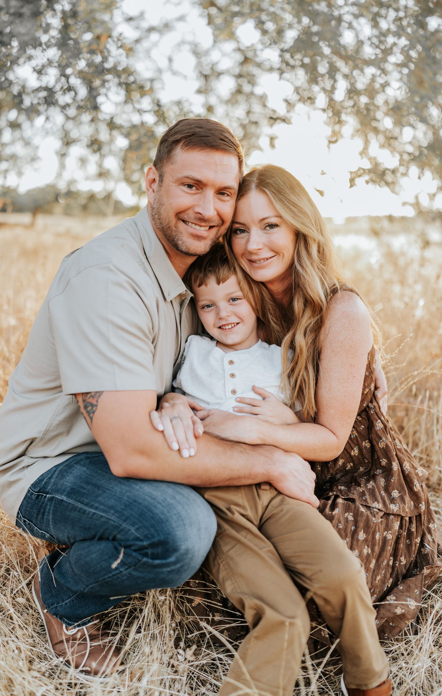 Family portrait captured in a golden field during sunset with light bokeh effect in the background.