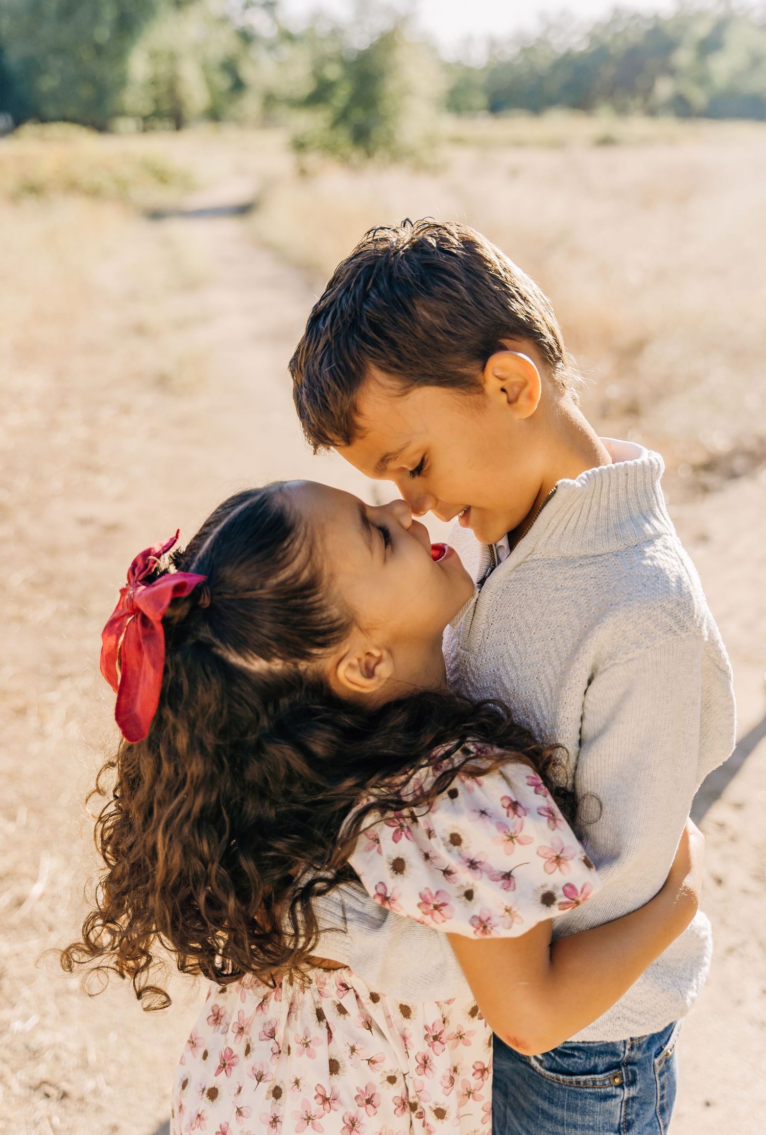 Two young children share a sweet embrace while playing outdoors on a sunny afternoon.