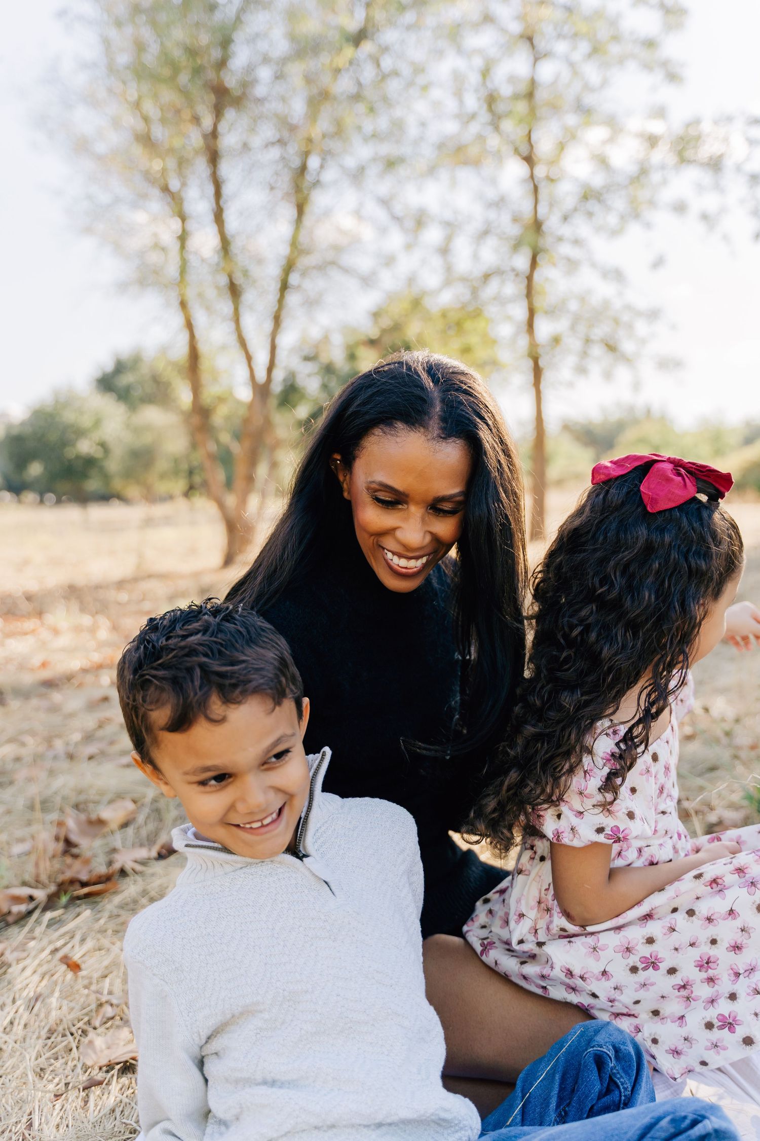 A heartwarming outdoor scene of a family sharing laughter while sitting together on the ground.