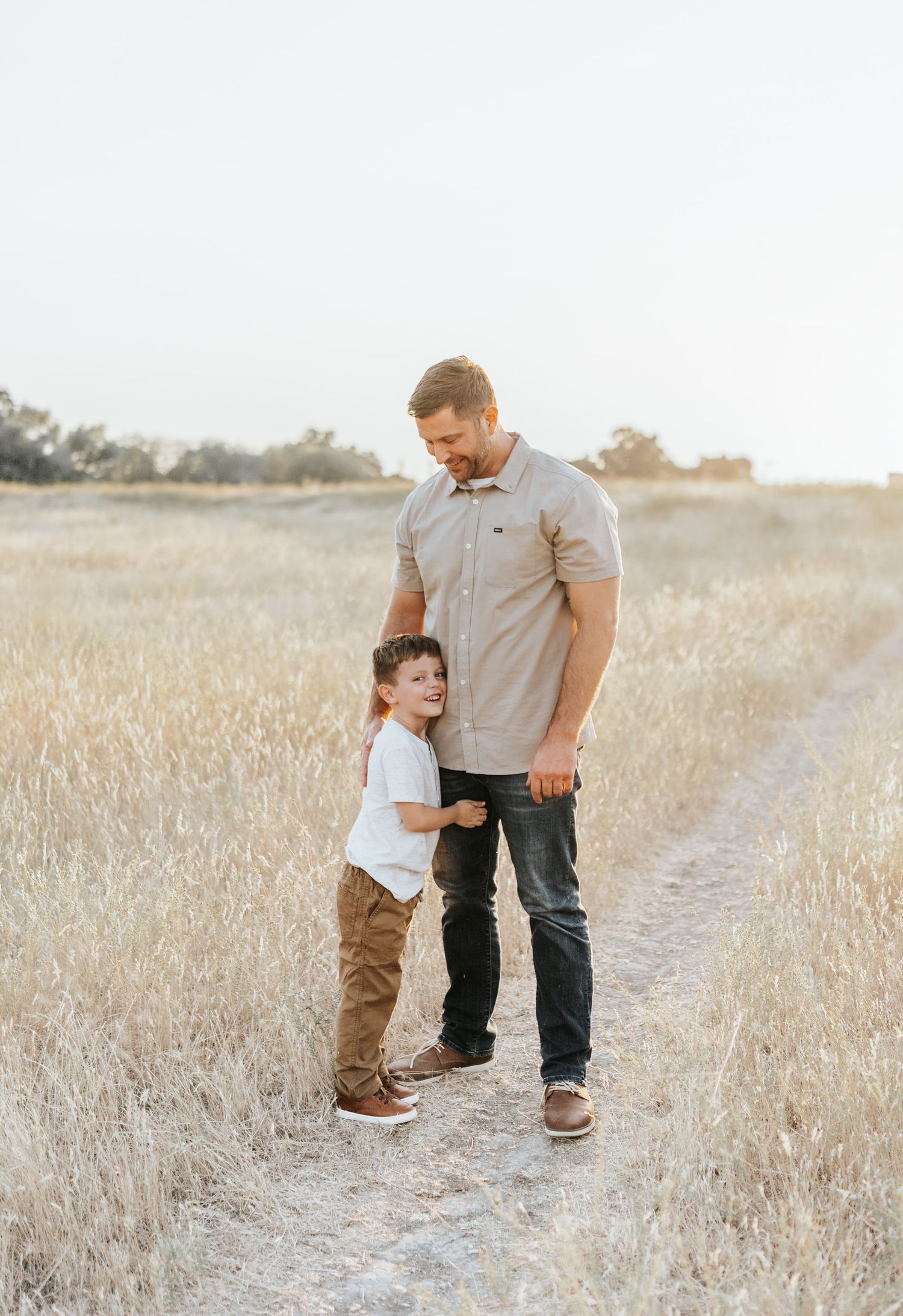 Parent and child sharing playful moments together in a sun-drenched field.