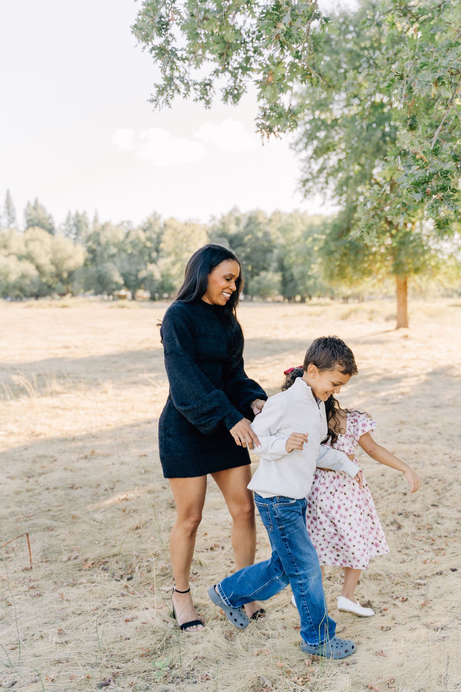 Candid family scene with children playing and laughing together in a natural outdoor setting.