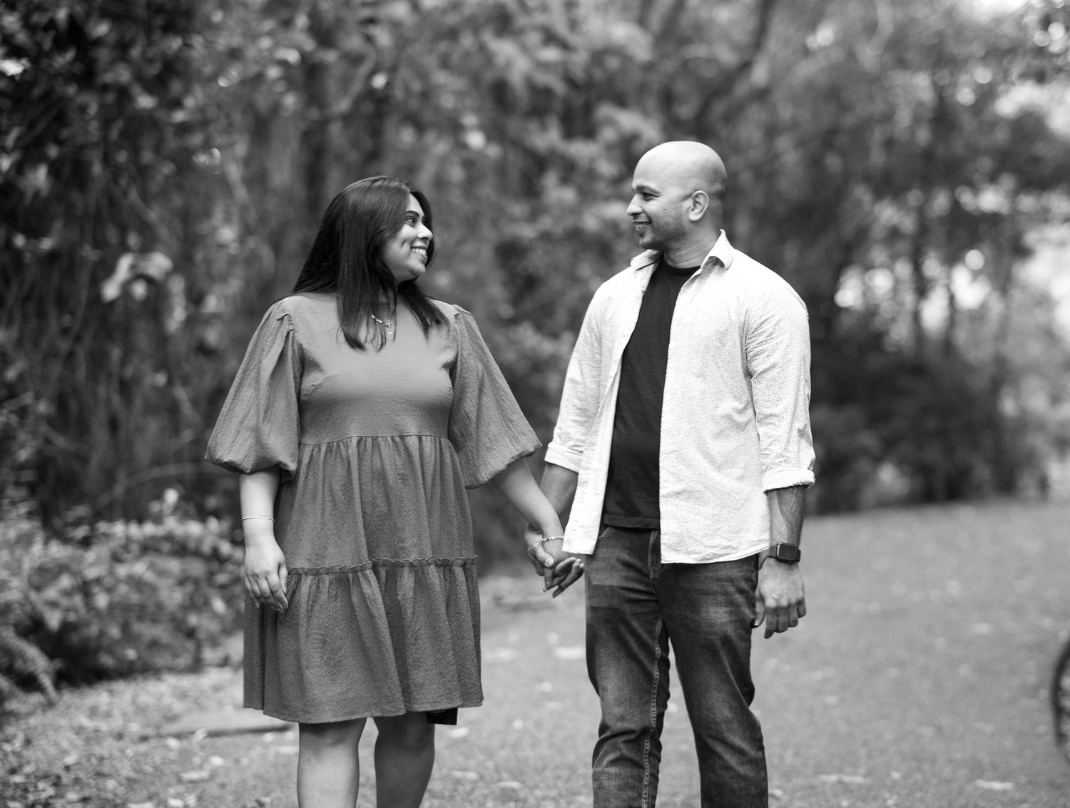 A couple strolls together through a scenic wooded area during an engagement session.