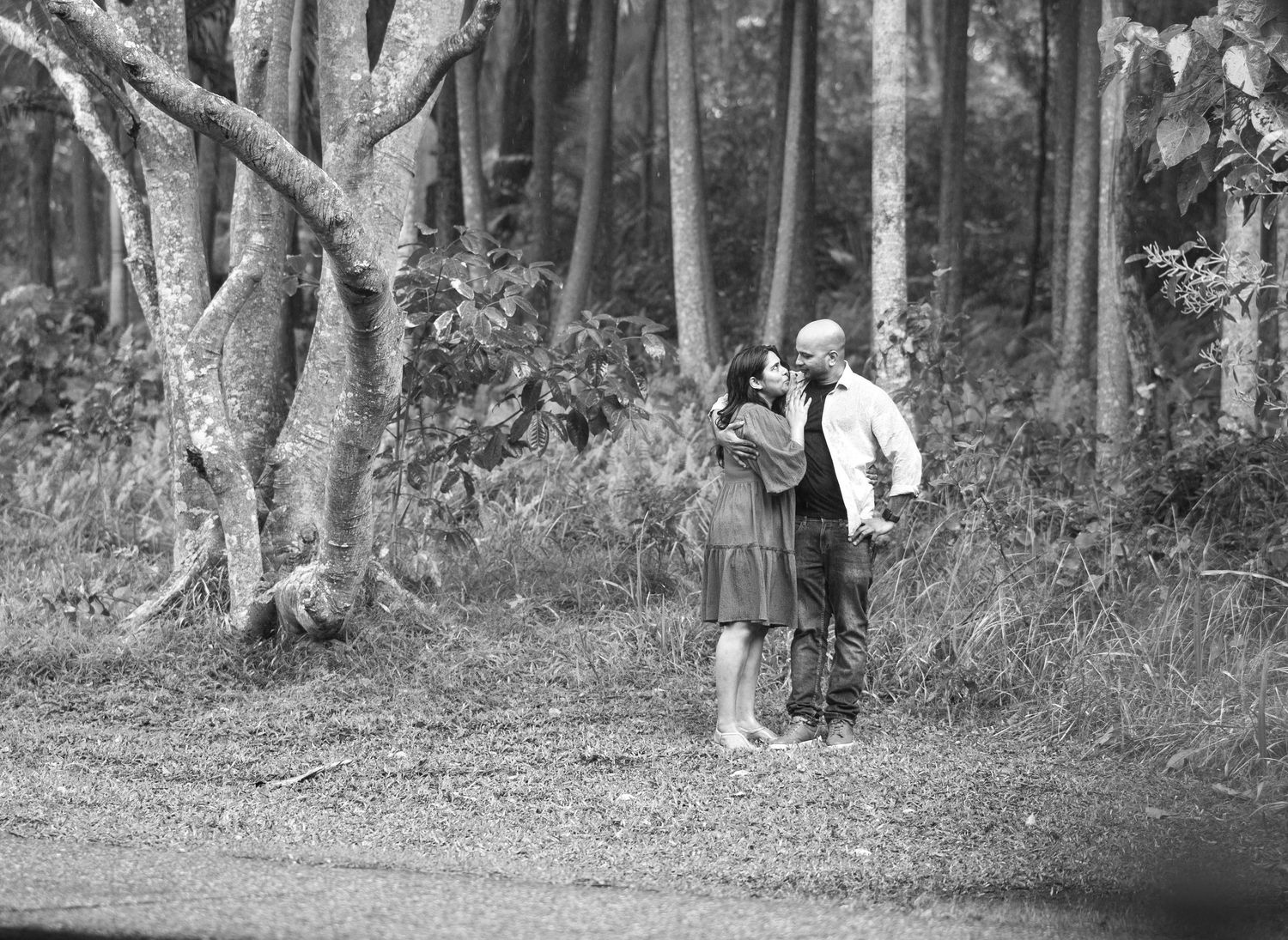 Natural outdoor portrait session in a serene wooded area with sunlight filtering through trees.