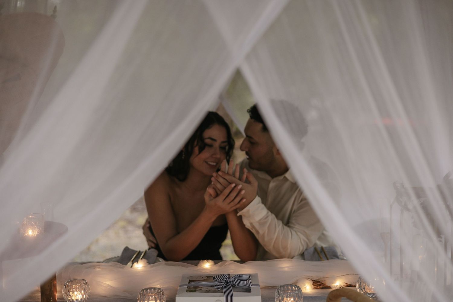 Romantic scene with draped white fabric and glowing candlelight.