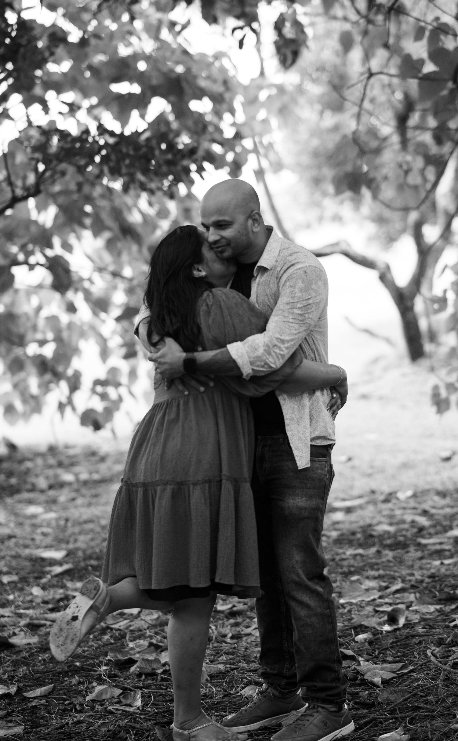 Black and white photo sequence showing tender moments between a couple in a wooded setting.