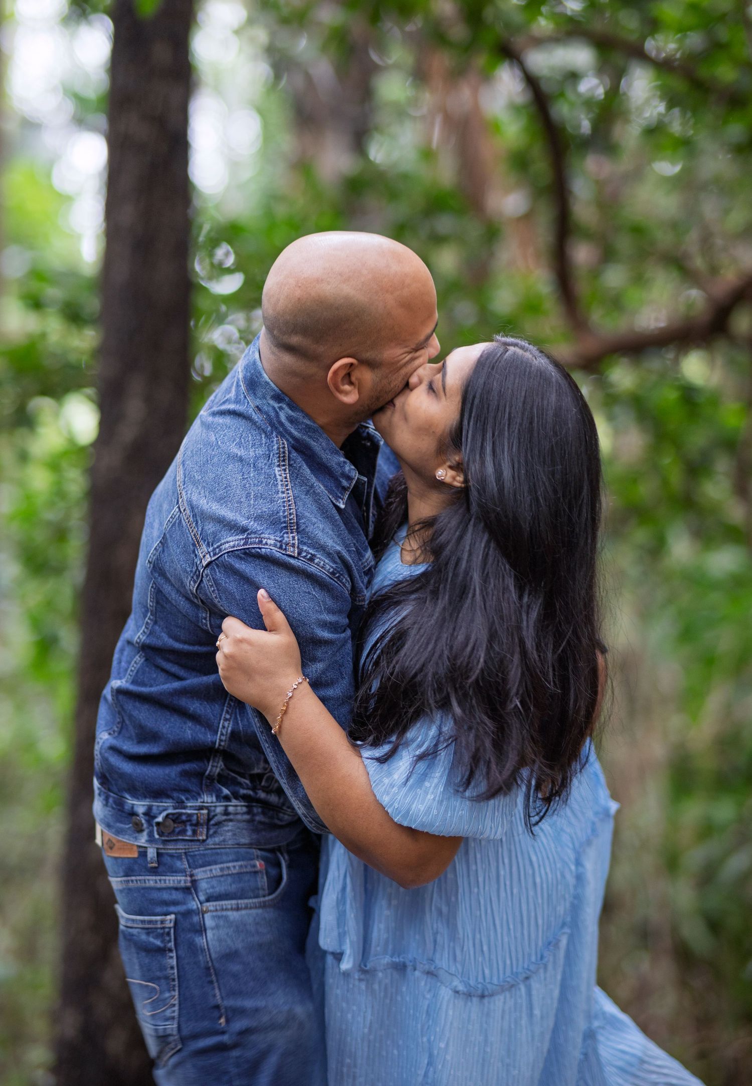 Romantic forest photoshoot capturing intimate moments between a couple in casual attire.