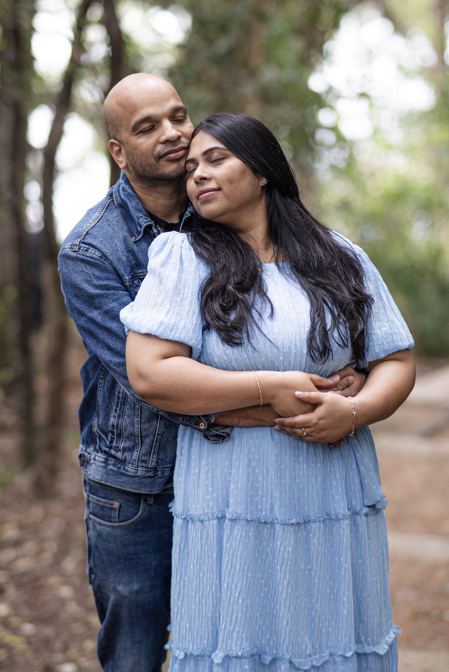 Tender embraces between a couple in coordinated denim and blue outfits during an outdoor photoshoot.
