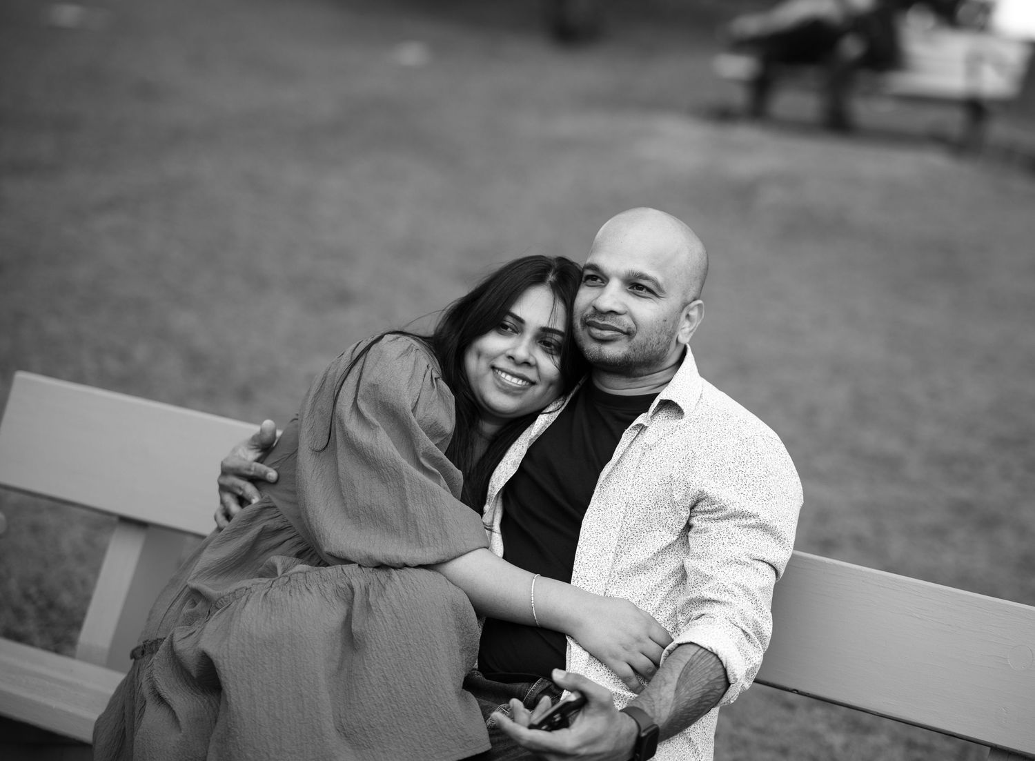 A couple shares a tender moment on park benches during an intimate photography session.