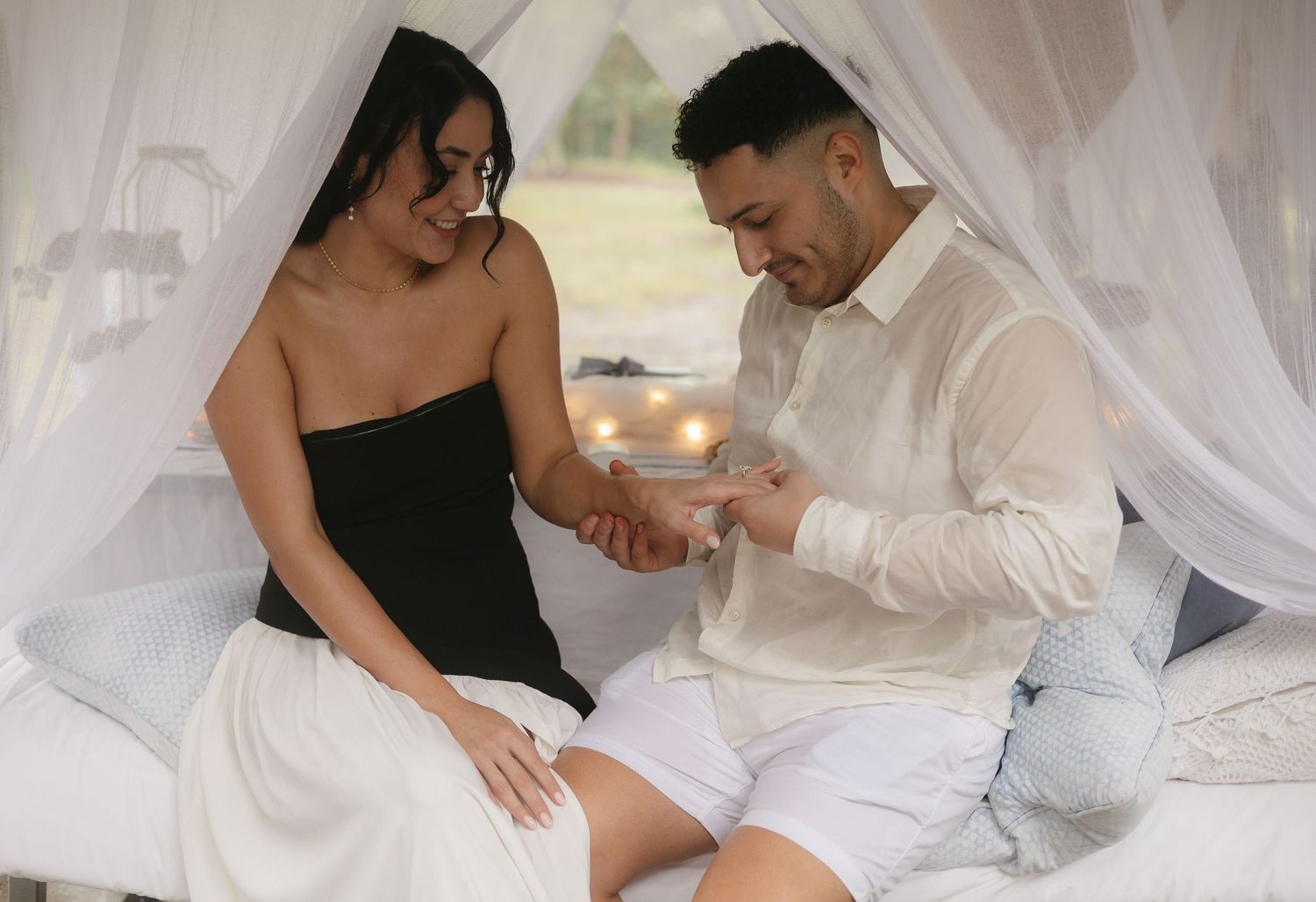 Intimate couple photoshoot with white draping fabric and soft lighting.